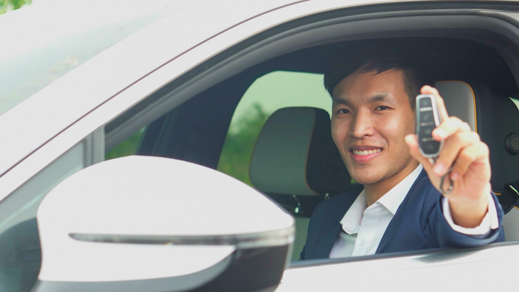 jong Aziatisch zakenman tonen een auto sleutel binnen zijn nieuw elektrisch voertuig. ev auto. foto
