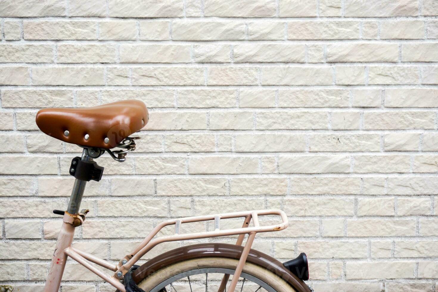 detailopname en Bijsnijden retro fiets Aan wit bakstenen muur achtergrond met ruimte voor teksten. foto