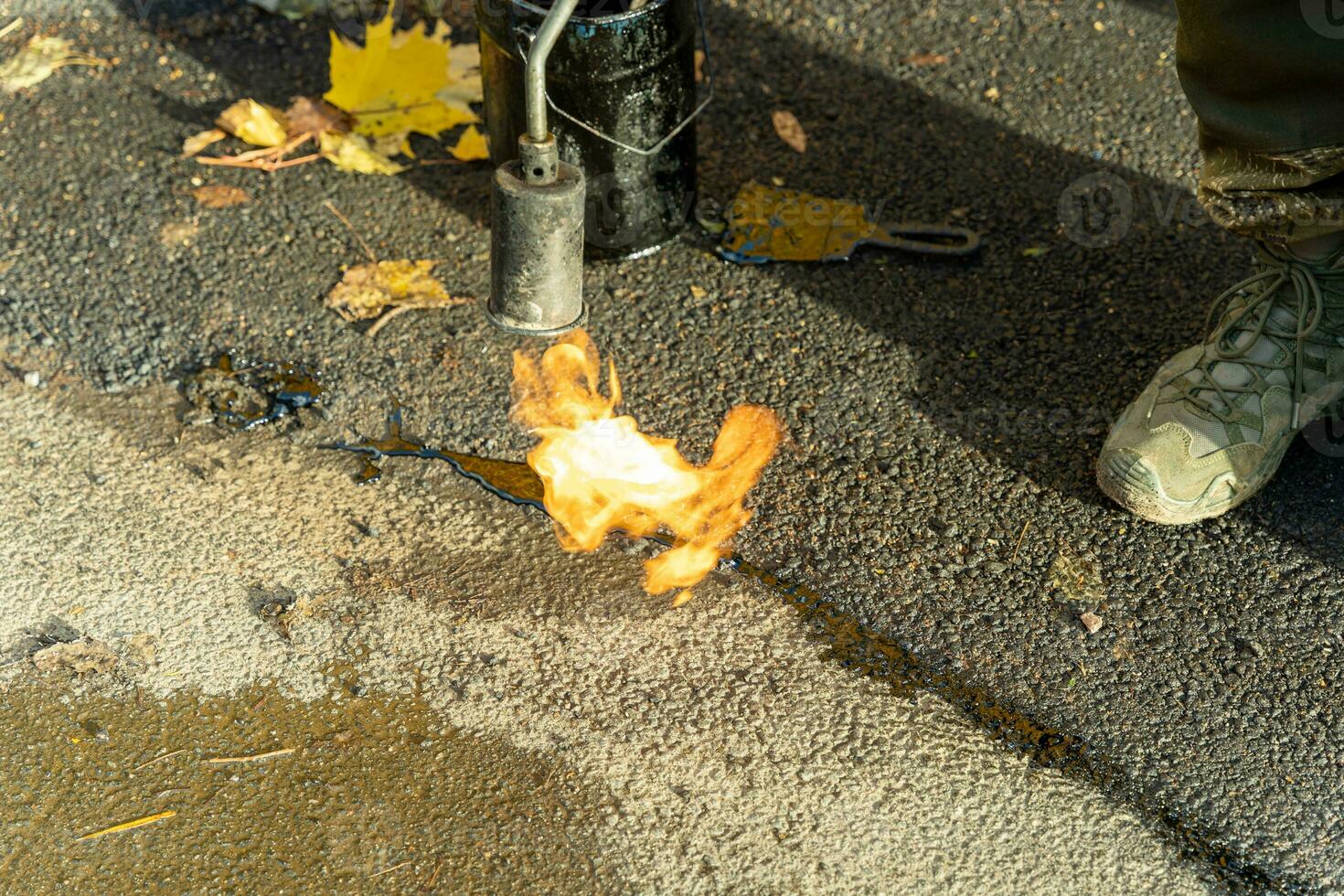 repareren asfalt scheuren met vurig vlam gas- brander en mastiek afdichtmiddel foto