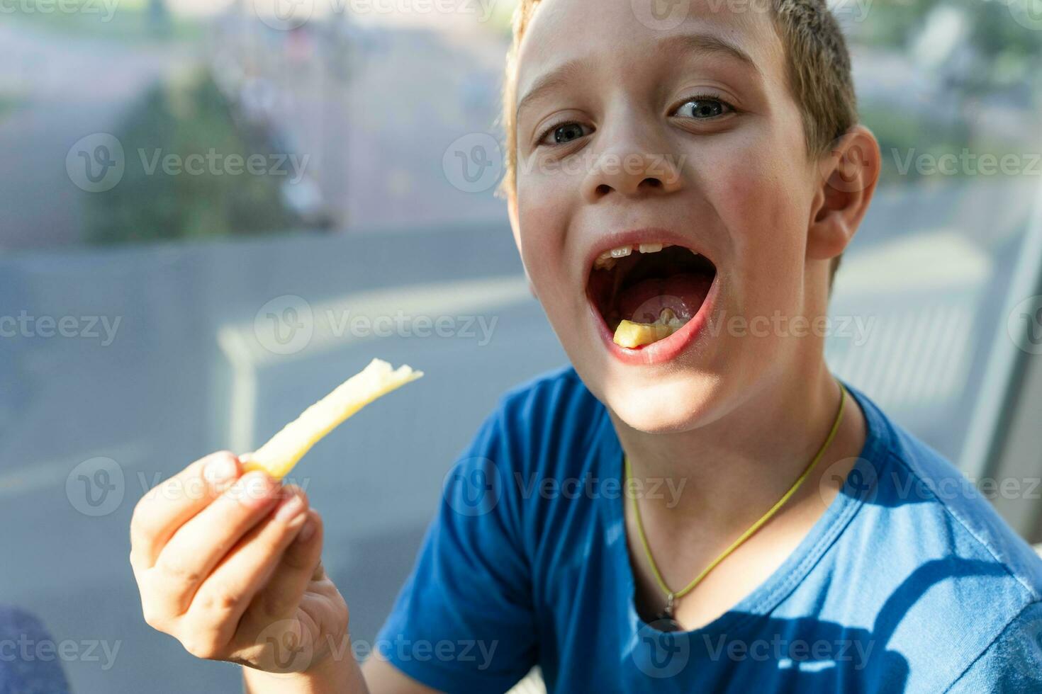 schattig Kaukasisch jongen genieten van aan het eten Frans Patat Bij een cafe tafel foto