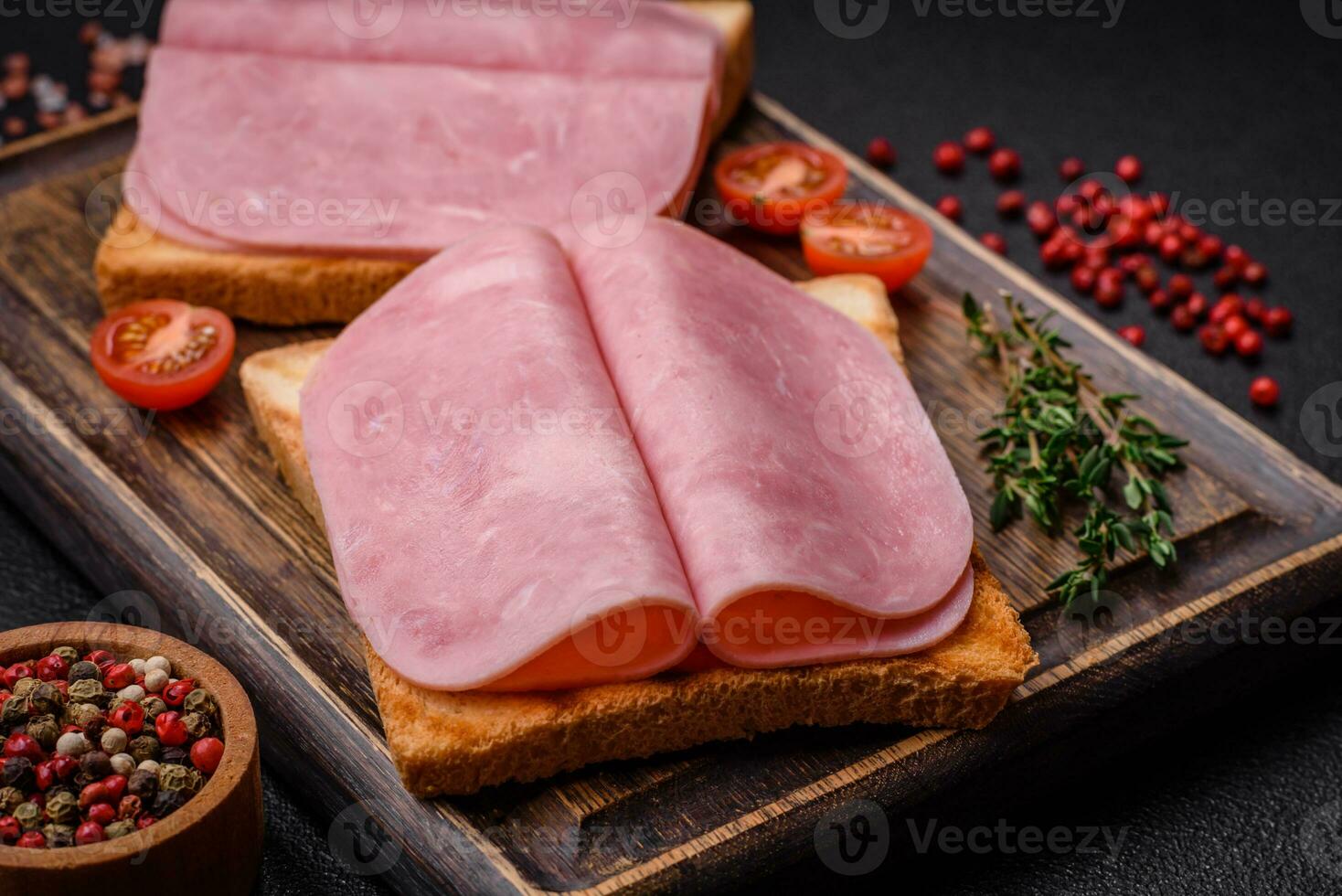 heerlijk belegd broodje met geroosterd brood brood, ham, tomaten, zout en specerijen foto