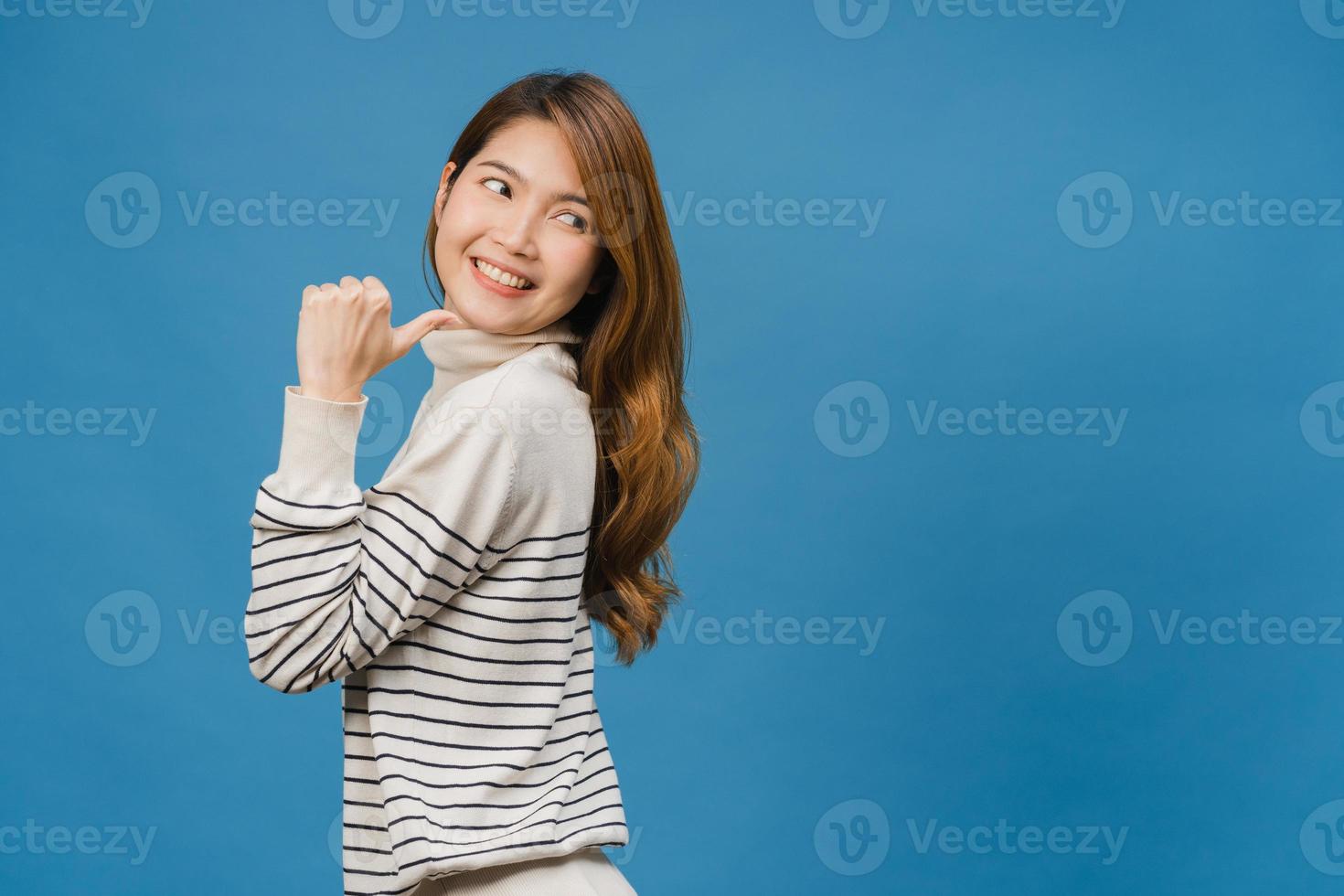 portret van een jonge aziatische dame die lacht met een vrolijke uitdrukking, toont iets geweldigs op lege ruimte in casual kleding en staat geïsoleerd op een blauwe achtergrond. gezichtsuitdrukking concept. foto