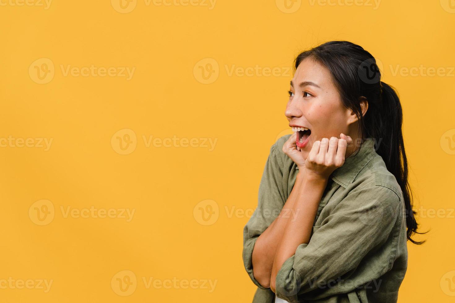 jonge aziatische dame voelt geluk met positieve uitdrukking, vrolijke verrassing funky, gekleed in casual doek geïsoleerd op gele achtergrond. gelukkige schattige blije vrouw verheugt zich over succes. gezichtsuitdrukking. foto