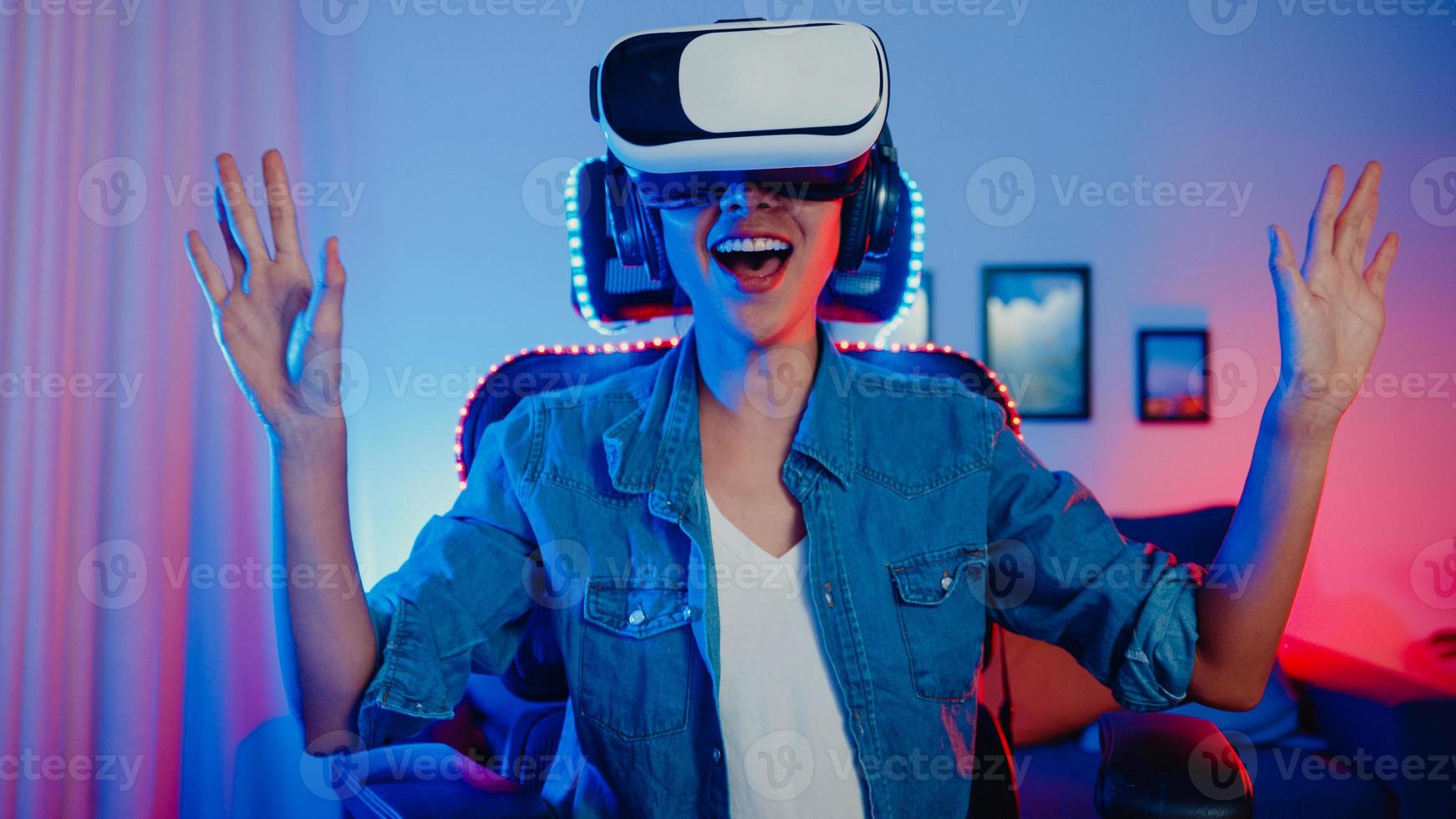 gelukkig aziatisch meisje draagt virtual reality-bril bril headset voelt verrassing echt spelprogramma 's nachts in haar neon-thuisstudio, jonge vrouw raakt de lucht aan, de vr-ervaring, thuisquarantaine-activiteit. foto