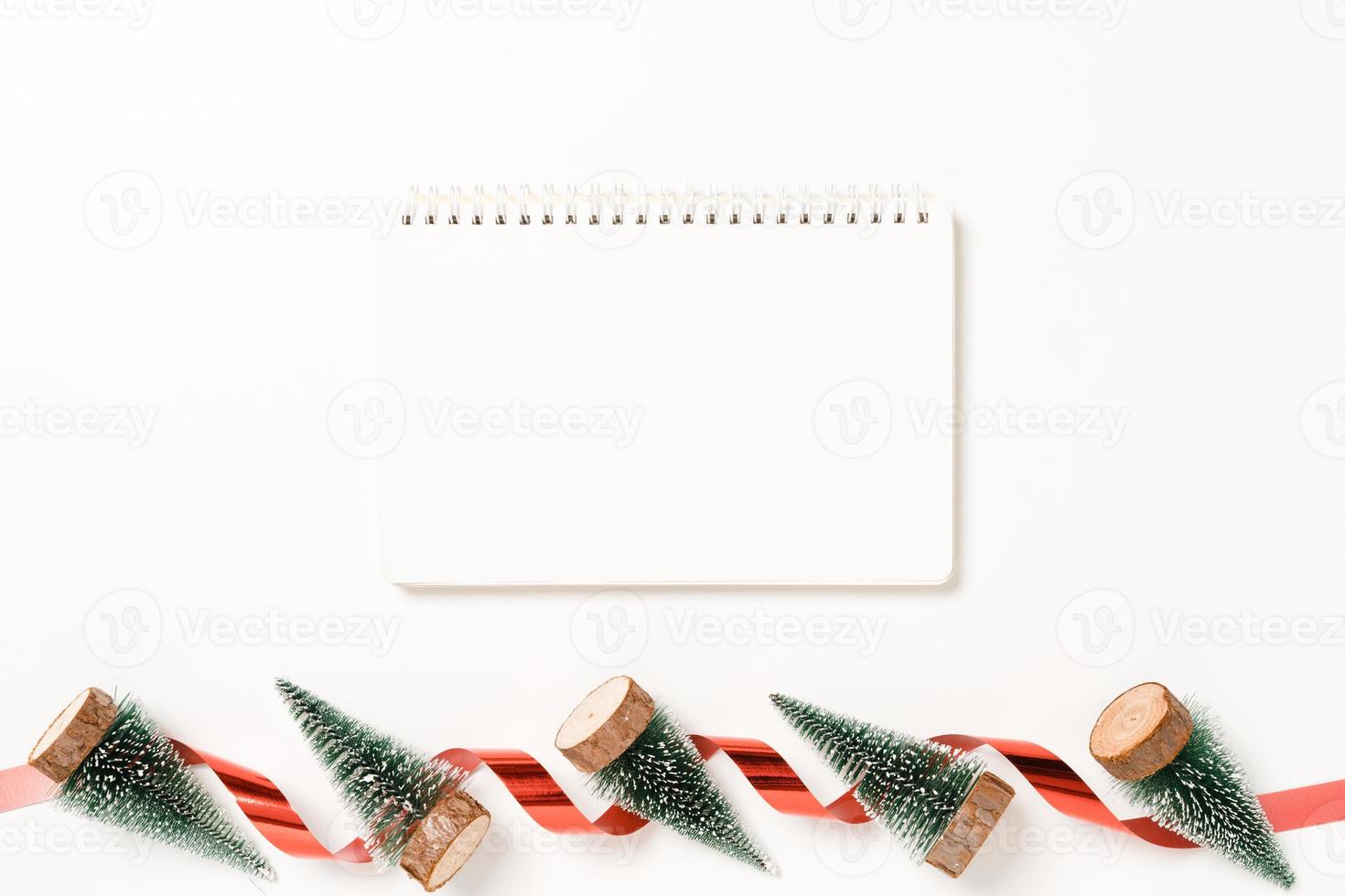 minimale creatieve platte lay van winterkerst traditionele compositie en nieuwjaarsvakantieseizoen. bovenaanzicht open mockup zwarte notebook voor tekst op witte achtergrond. bespotten en kopiëren van ruimtefotografie. foto