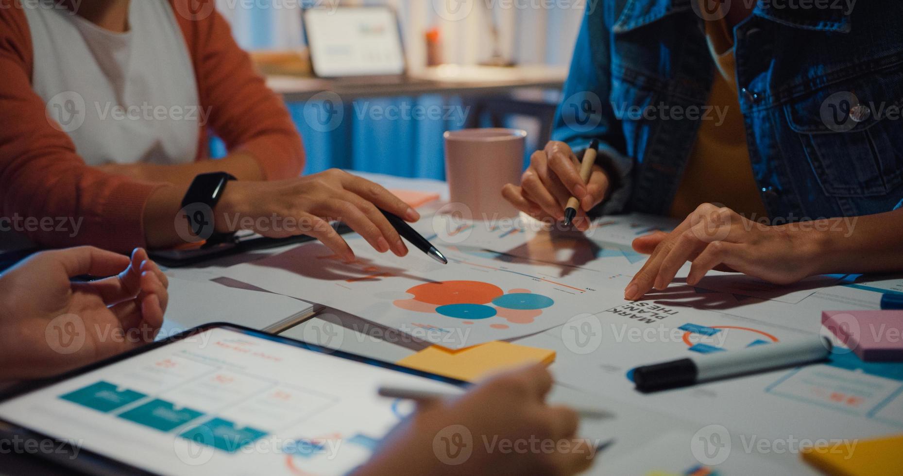 millennial azië mensen ontmoeten brainstormideeën over nieuw papierwerk projectcollega's die samenwerken plannen successtrategie genieten van teamwork in een klein modern nachtkantoor. collega teamwerk concept. foto