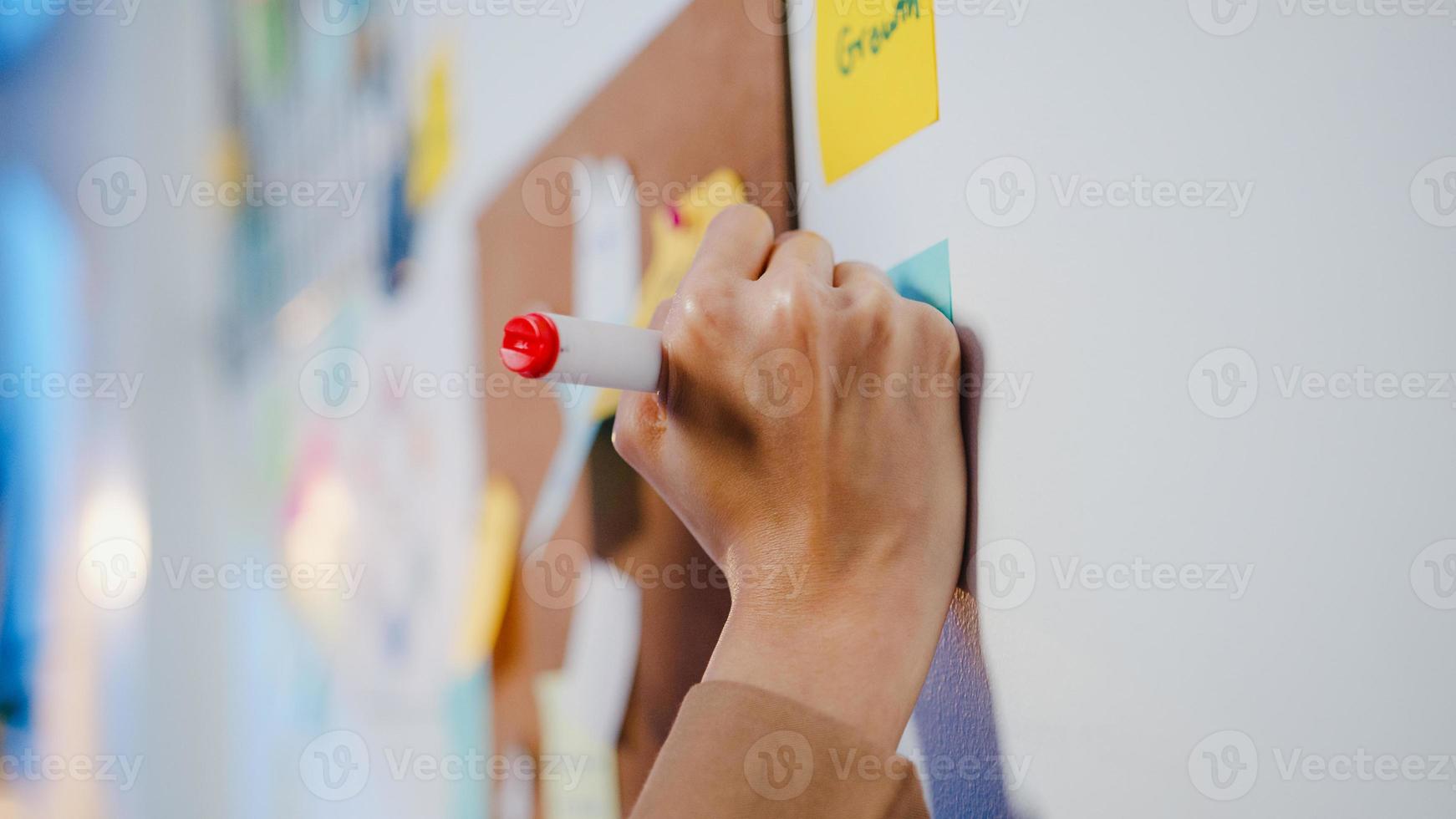 groep jonge ondernemers uit Azië die zakelijke brainstormvergadering bespreken, samenwerken om gegevens te delen en whiteboard op de muur te schrijven met een plakbriefje in het nachtkantoor. collega teamwerk concept. foto