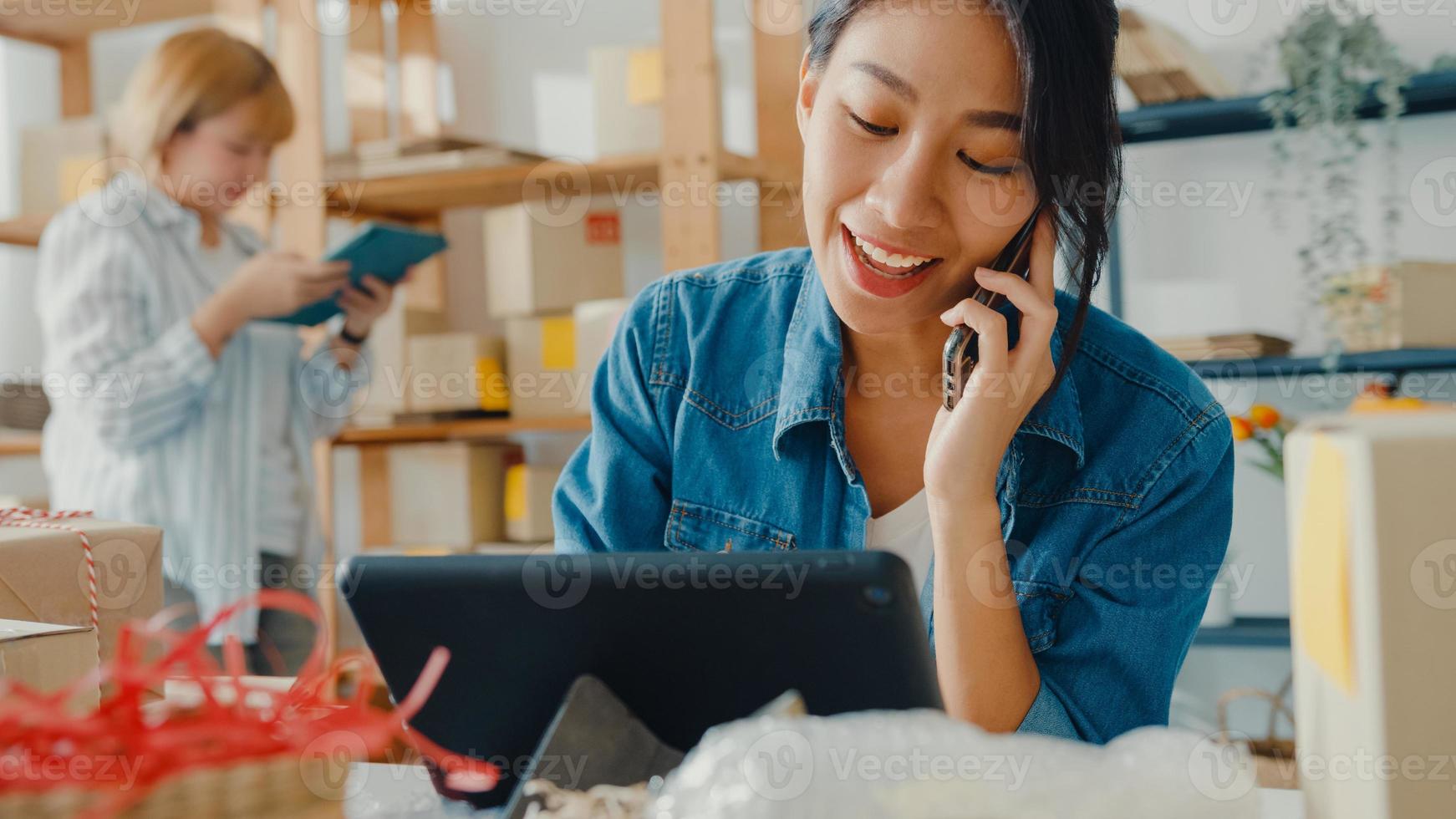 jonge Aziatische zakenvrouwen die mobiel bellen en een inkooporder ontvangen en het product op voorraad controleren op het thuiskantoor. eigenaar van een klein bedrijf, online marktlevering, lifestyle freelance concept. foto