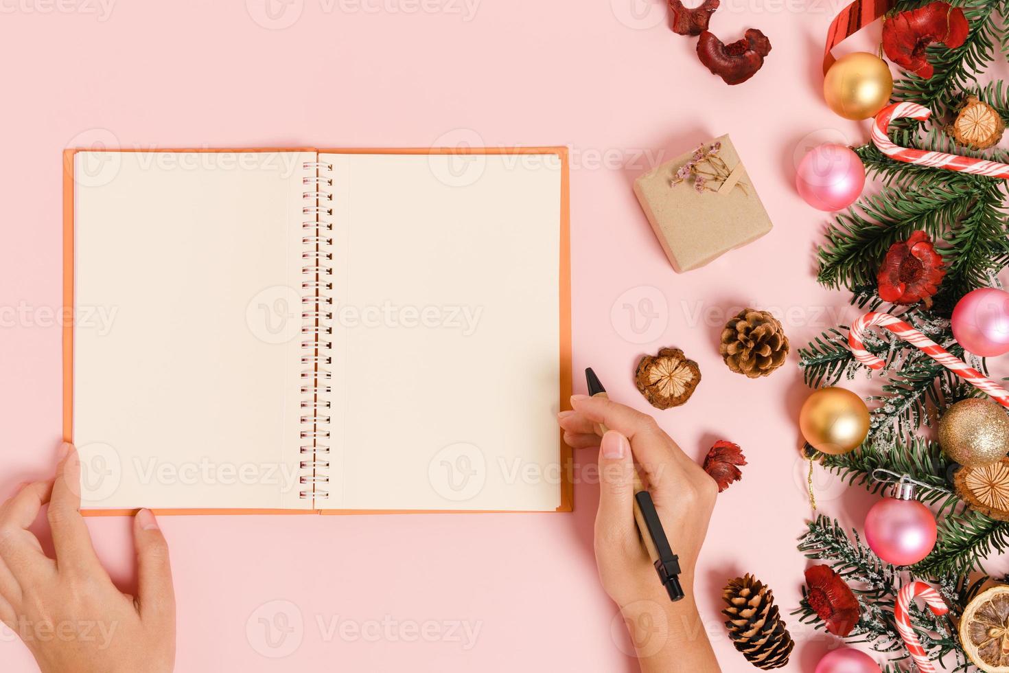 minimale creatieve platte lay van winterkerst traditionele compositie en nieuwjaarsvakantieseizoen. bovenaanzicht open mockup zwarte notebook voor tekst op roze achtergrond. bespotten en kopiëren van ruimtefotografie. foto