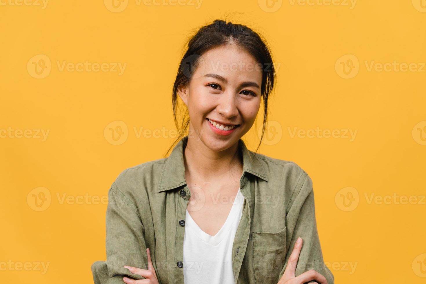 portret van jonge Aziatische dame met positieve uitdrukking, armen gekruist, breed glimlachen, gekleed in casual kleding en camera kijken over gele achtergrond. gelukkige schattige blije vrouw verheugt zich over succes. foto