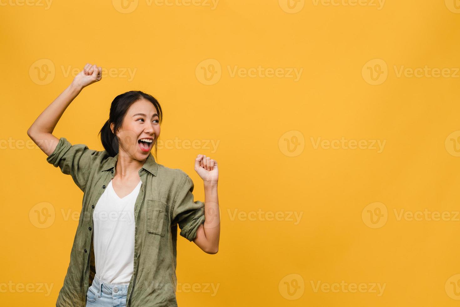 portret van jonge Aziatische dame met positieve uitdrukking, breed glimlachen, gekleed in casual kleding op gele achtergrond. gelukkige schattige blije vrouw verheugt zich over succes. gezichtsuitdrukking concept. foto