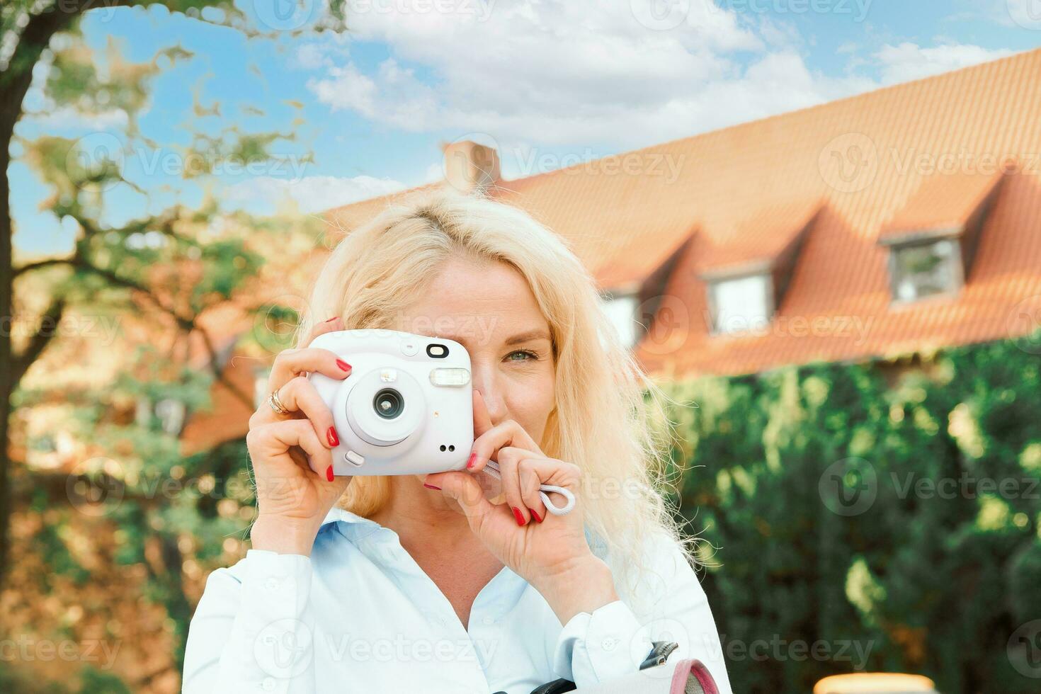 een jong vrouw Aan de straat duurt afbeeldingen Aan een polaroid. een warm zomer dag. de vrouw looks in de camera. foto