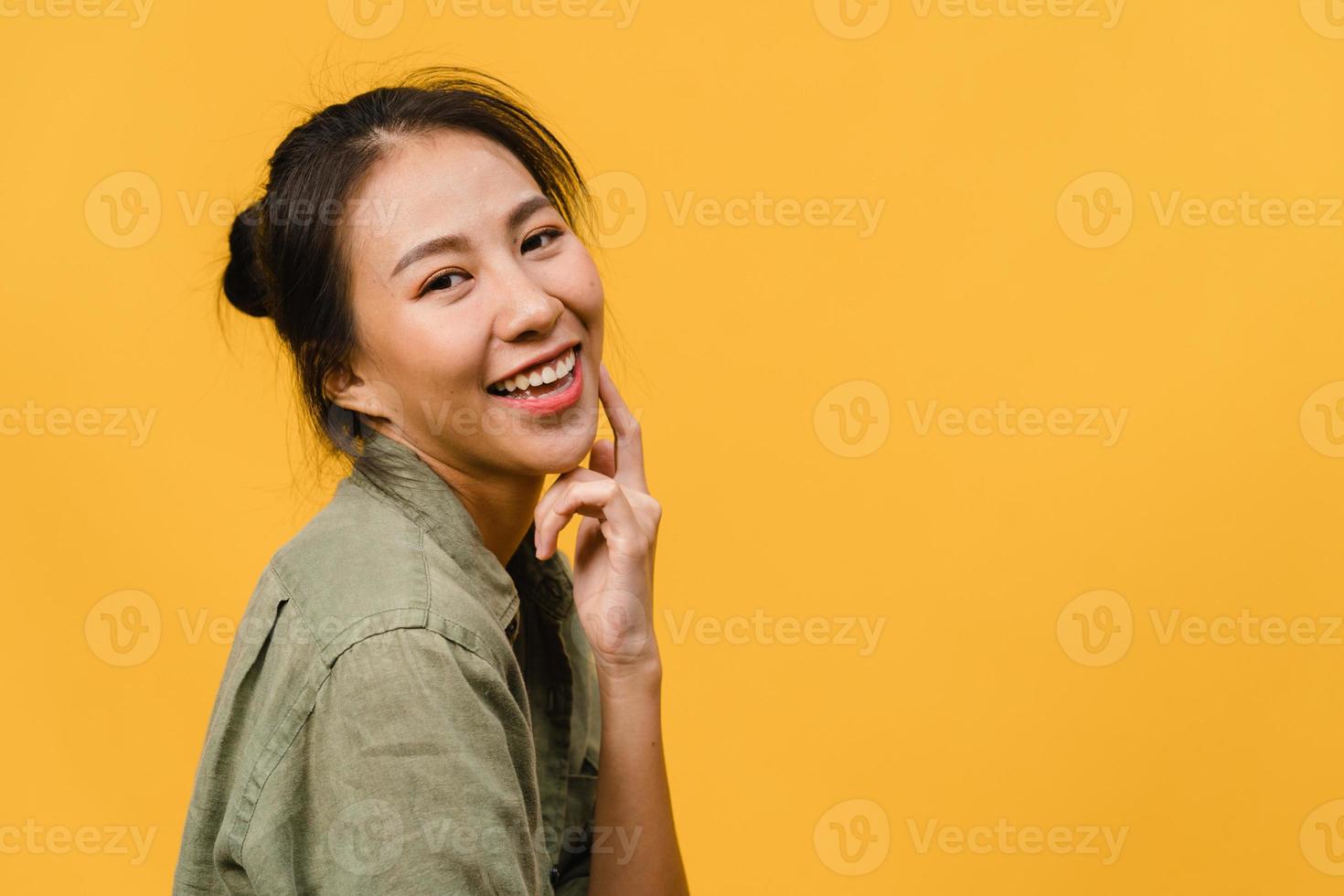 jonge azië dame met positieve uitdrukking, breed glimlachen, gekleed in casual kleding en camera kijken over gele achtergrond. gelukkige schattige blije vrouw verheugt zich over succes. gezichtsuitdrukking concept. foto