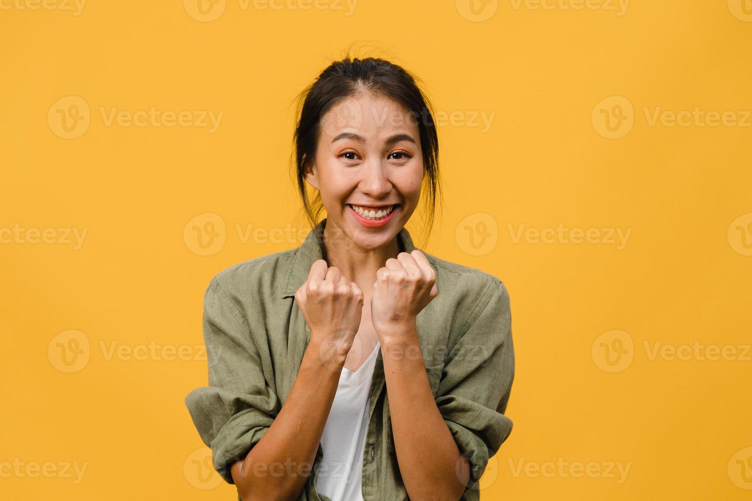 jonge aziatische dame met positieve uitdrukking, vrolijk en opwindend, gekleed in een casual doek en kijk naar de camera over gele achtergrond. gelukkige schattige blije vrouw verheugt zich over succes. gezichtsuitdrukking concept. foto