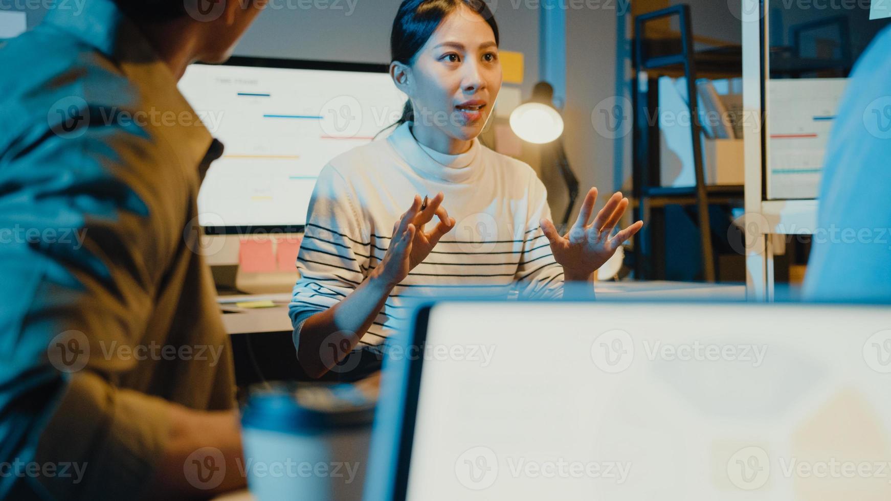 Azië zakenmensen staan achter transparante glazen wand luisteren manager wijst voortgangswerk en brainstormvergadering en werknemer post plakkerige nota in kantoor nacht. zakelijke inspiratie, ideeën delen. foto