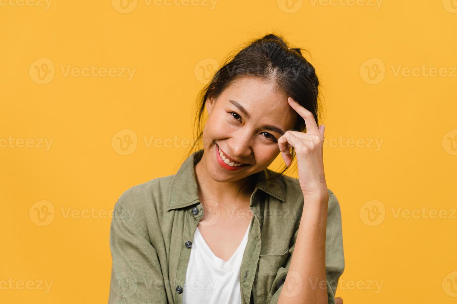 jonge azië dame met positieve uitdrukking, breed glimlachen, gekleed in casual kleding en camera kijken over gele achtergrond. gelukkige schattige blije vrouw verheugt zich over succes. gezichtsuitdrukking concept. foto