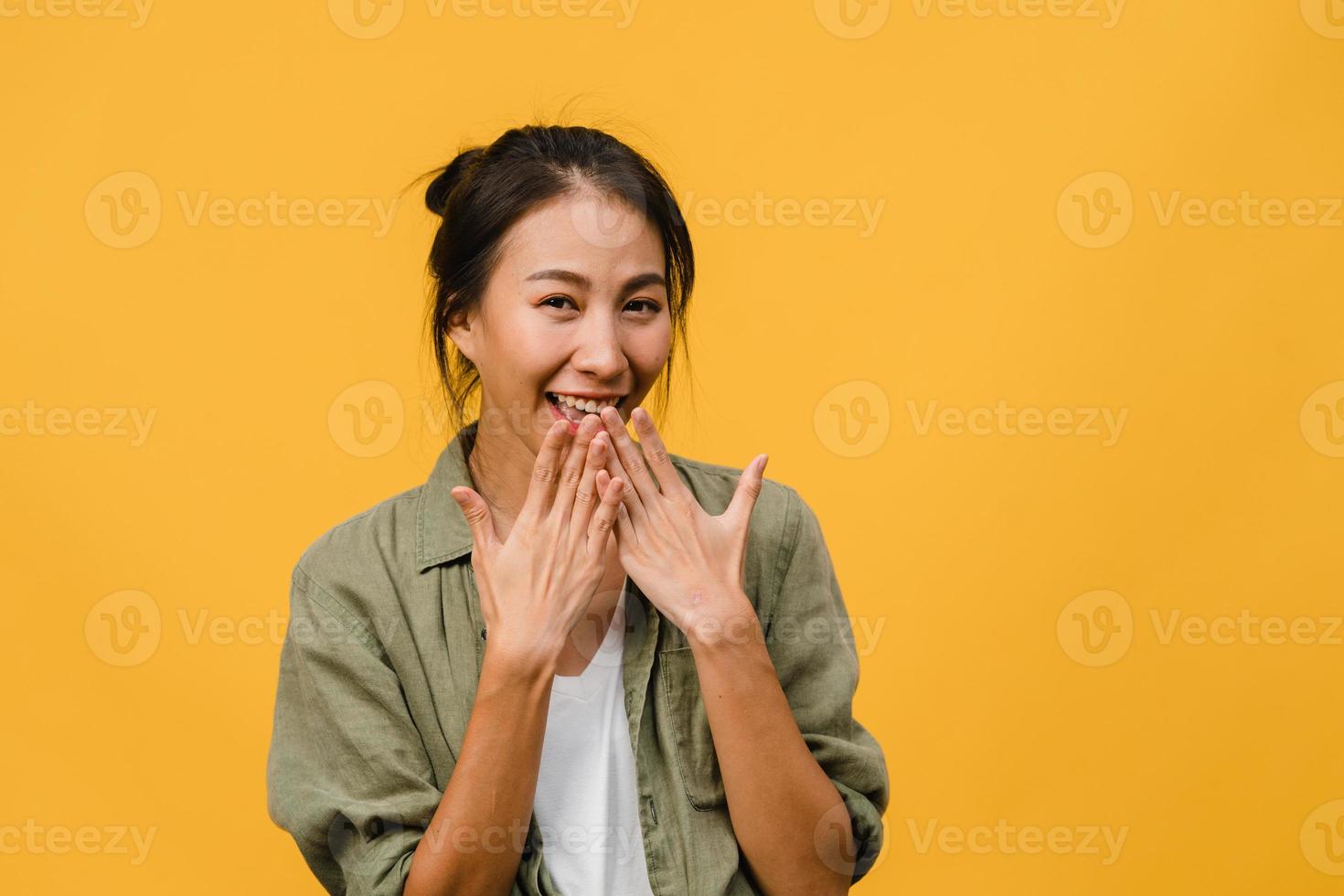 jonge azië dame met positieve uitdrukking, breed glimlachen, gekleed in casual kleding en camera kijken over gele achtergrond. gelukkige schattige blije vrouw verheugt zich over succes. gezichtsuitdrukking concept. foto