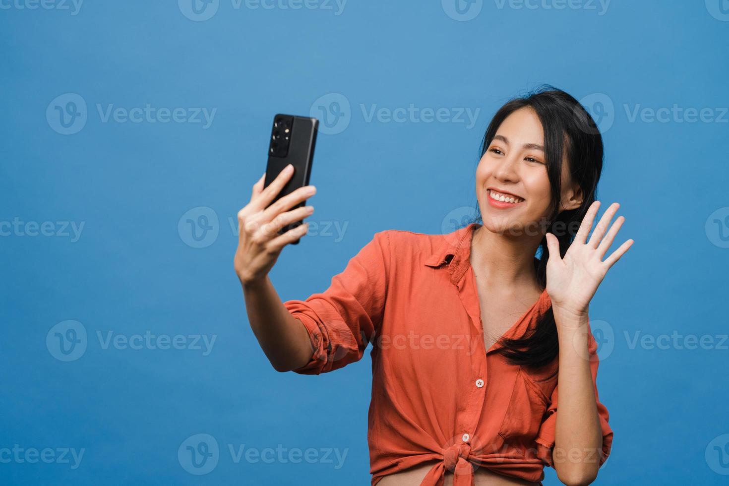 lachende schattige Aziatische vrouw selfie foto maken op slimme telefoon met positieve uitdrukking in casual kleding en staan geïsoleerd op blauwe achtergrond. gelukkige schattige blije vrouw verheugt zich over succes.