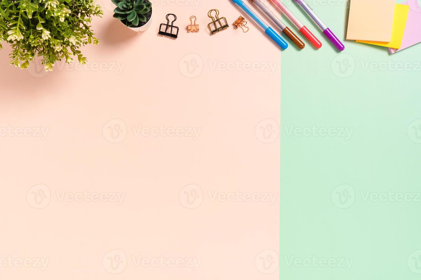 minimale werkruimte - creatieve platliggende foto van werkruimtebureau. bovenaanzicht bureau met zelfklevende notitie op pastel groen roze kleur achtergrond. bovenaanzicht met kopieerruimte, platliggende fotografie.