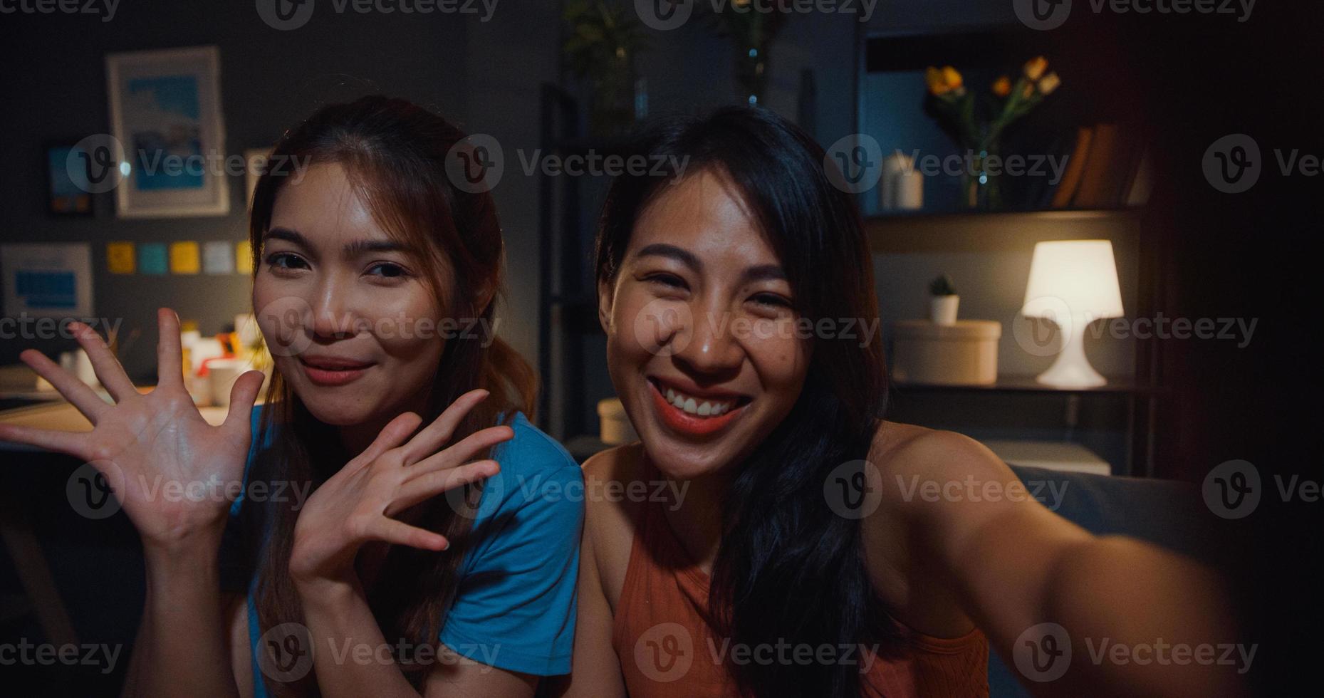 tiener azië vrouwen voelen zich gelukkig lachend selfie en kijken naar de camera met ontspannen in de woonkamer thuis 's nachts. vrolijke kamergenoot dames videogesprek met vriend en familie, lifestyle vrouw thuis concept. foto