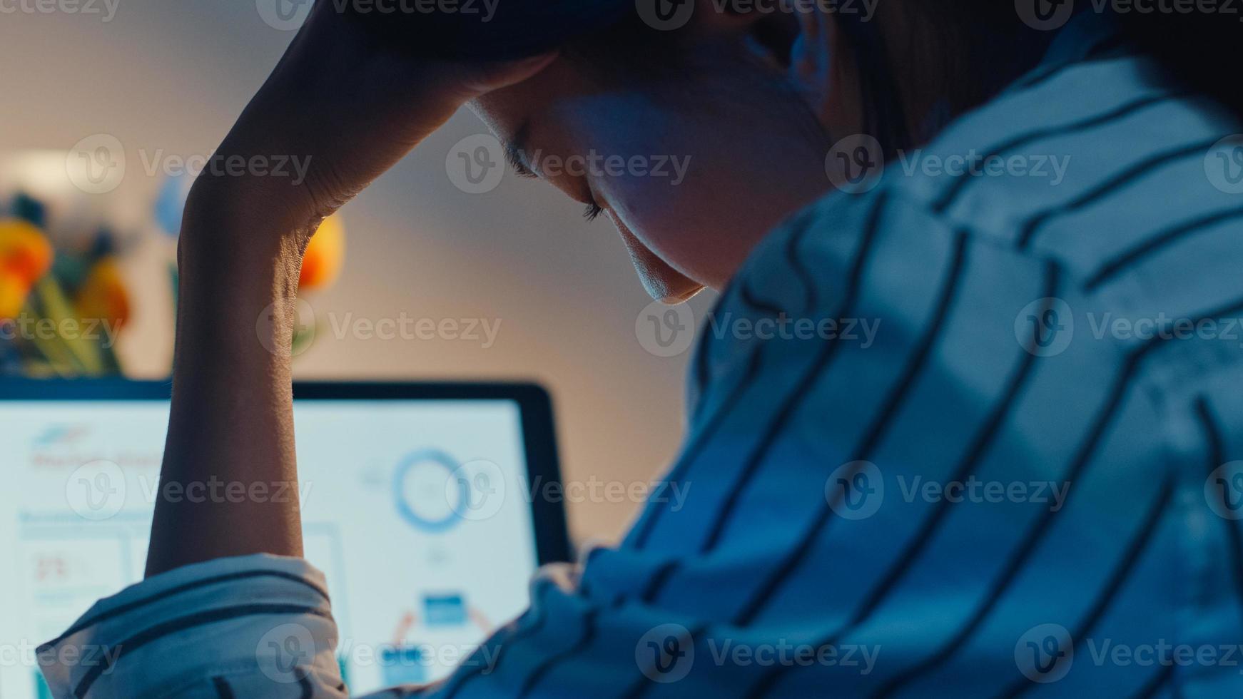 jonge aziatische dame werknemer werkt overuren 's avonds laat stress financieren boekhoudkundig projectonderzoek op laptop thuis. studente leert online thuis, sociale afstand, nieuw normaal thuiswerkconcept. foto