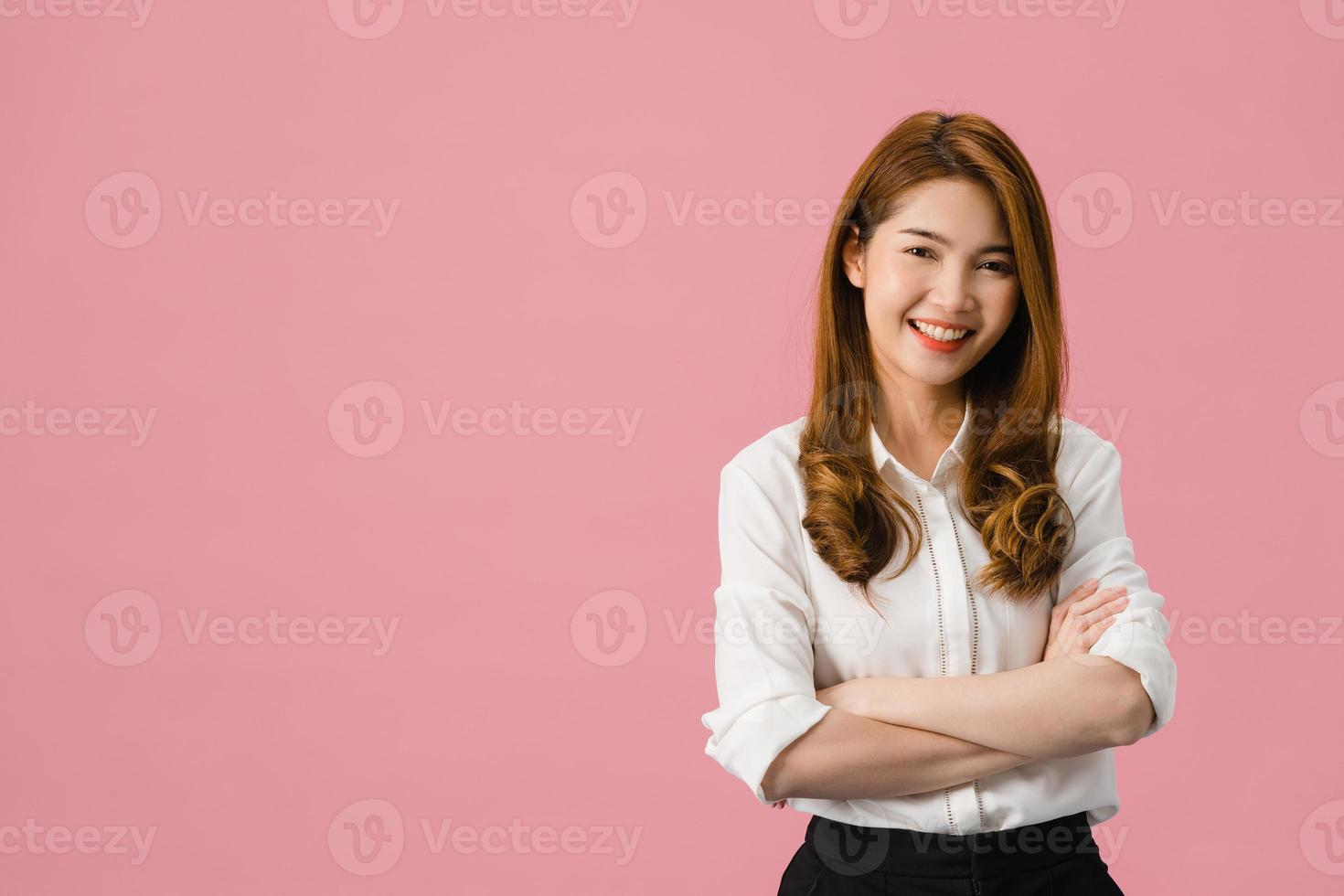 portret van jonge Aziatische dame met positieve uitdrukking, armen gekruist, breed glimlachen, gekleed in casual kleding en camera kijken over roze achtergrond. gelukkige schattige blije vrouw verheugt zich over succes. foto