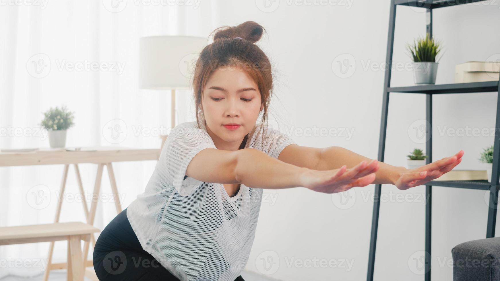 jonge Koreaanse dame in sportkledingoefeningen die aan het trainen zijn en laptop gebruiken om thuis yoga-videotutorials te bekijken. afstandstraining met personal trainer, sociale afstand, online onderwijsconcept. foto