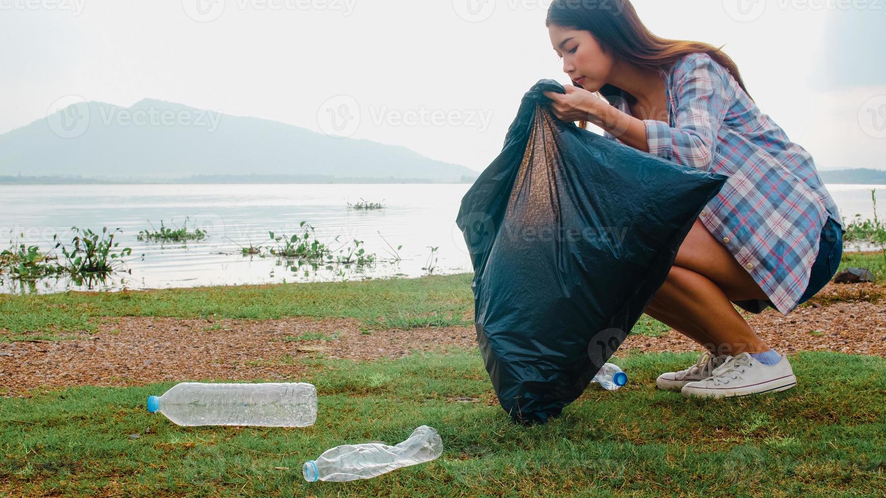 gelukkige jonge azië-activisten die plastic afval verzamelen op het strand. Koreaanse vrouwelijke vrijwilligers helpen de natuur schoon te houden en vuilnis op te halen. concept over milieubehoud vervuilingsproblemen. foto