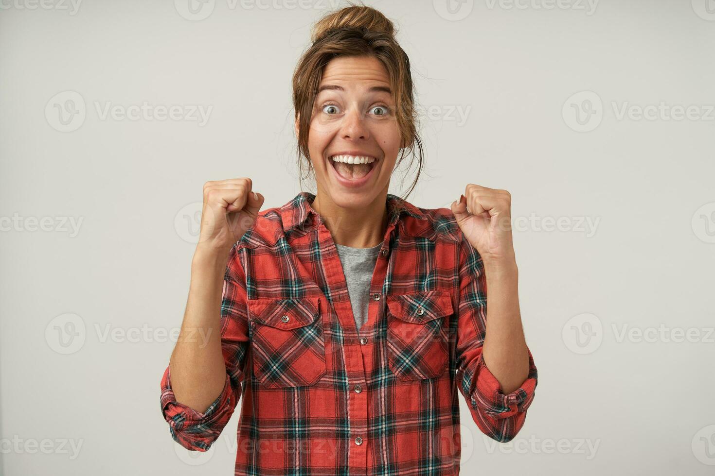 opgewonden jong aantrekkelijk brunette vrouw met natuurlijk bedenken verhogen emotioneel haar handen terwijl op zoek opgewonden Bij camera, staand over- wit achtergrond foto