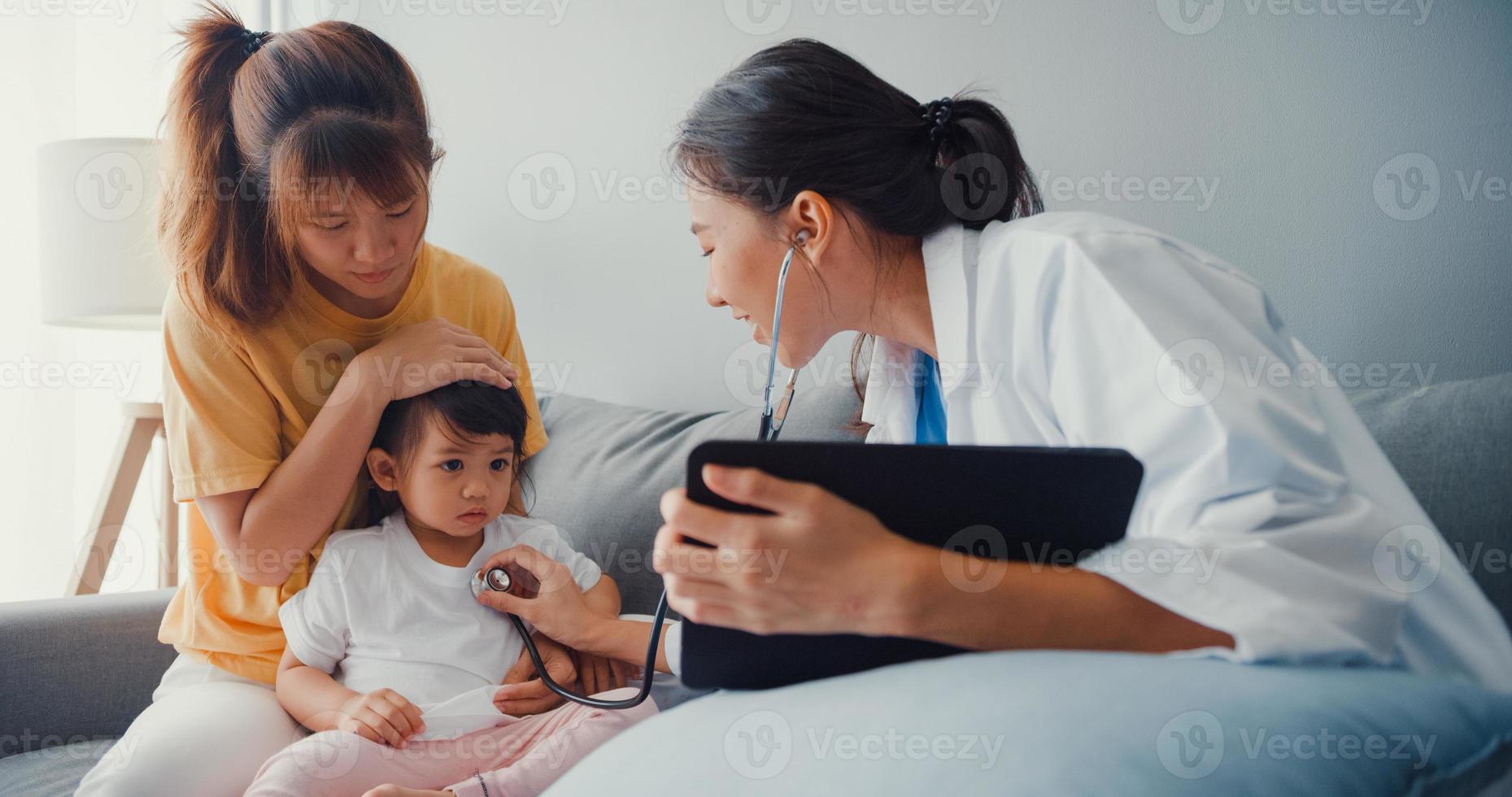 jonge azië vrouwelijke kinderarts houden stethoscoop examen meisje patiënt bezoek arts met moeder zitten op de bank in de woonkamer in huis. medische zorgverzekering, bezoek patiënt thuis concept. foto