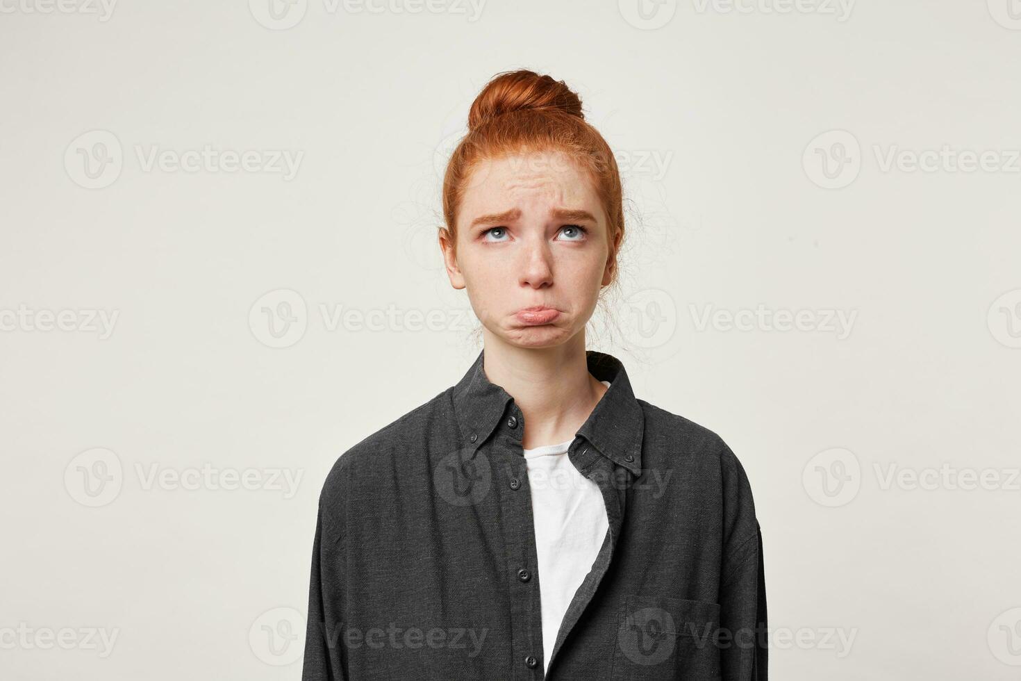 een jong roodharig meisje looks omhoog met droefheid, deed niet vind haar naam Aan de lijst, was laat voor de benoemd tijd, beeldt af een belediging, fronsen en plakken uit haar lager lip foto