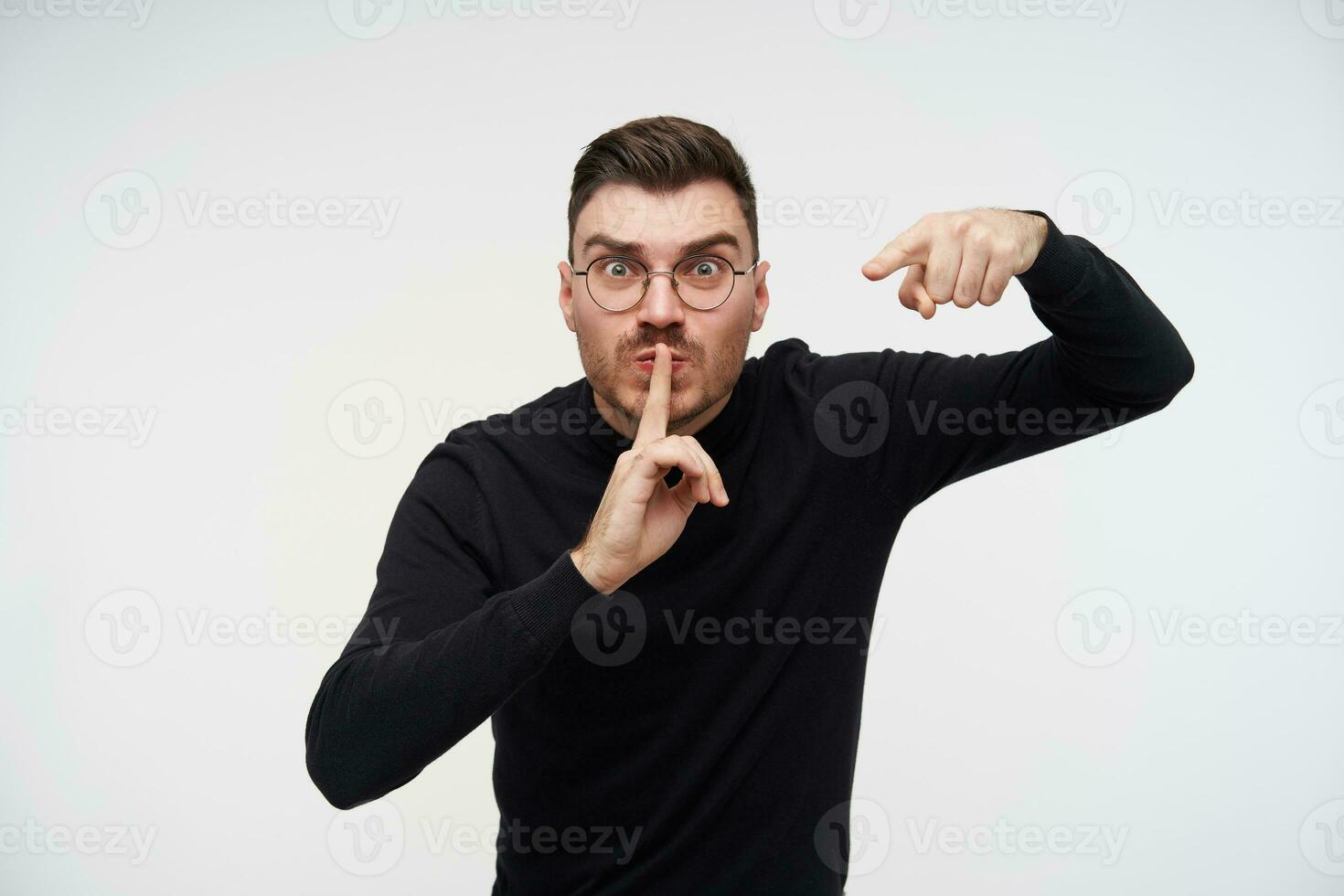 portret van jong boos kort haren brunette mannetje richten dwars Bij camera met wijsvinger terwijl tonen stil gebaar, geïsoleerd over- wit achtergrond foto