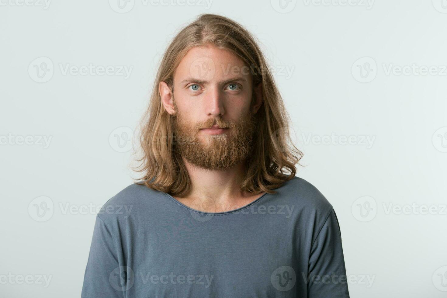 detailopname van echt aantrekkelijk jong Mens met baard en blond lang haar- draagt grijs t overhemd looks nadenkend en attent geïsoleerd over- wit achtergrond foto