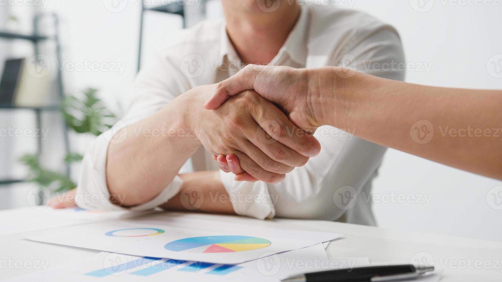 multiraciale groep jonge creatieve mensen in slimme vrijetijdskleding die zaken bespreken die samen handen schudden en glimlachen terwijl ze in een modern kantoor zitten. partnersamenwerking, teamwerkconcept voor collega's. foto