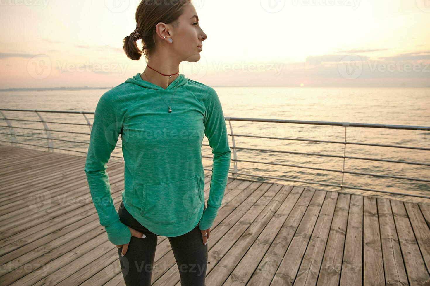 jong sportief vrouw draagt in sportkleding, treinen Bij de kust, maakt ochtend- uitrekken. Gezondheid zorg concept. foto