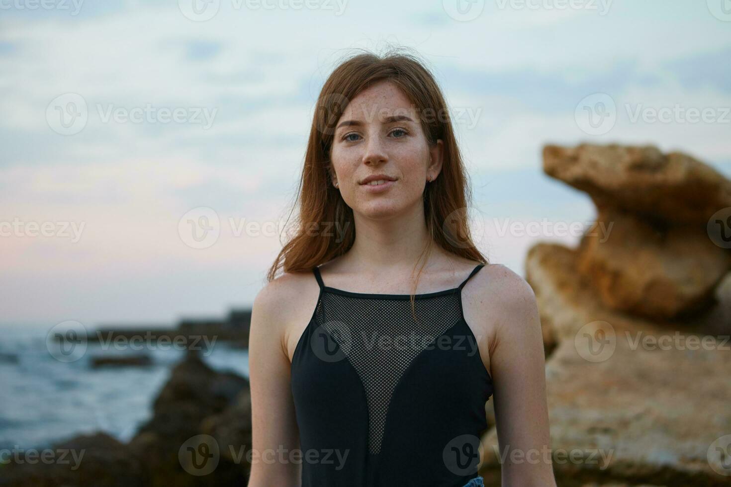 portret van jong roodharige schattig dame met sproeten Aan de strand, looks Bij de camera en glimlach, looks positief en gelukkig. foto