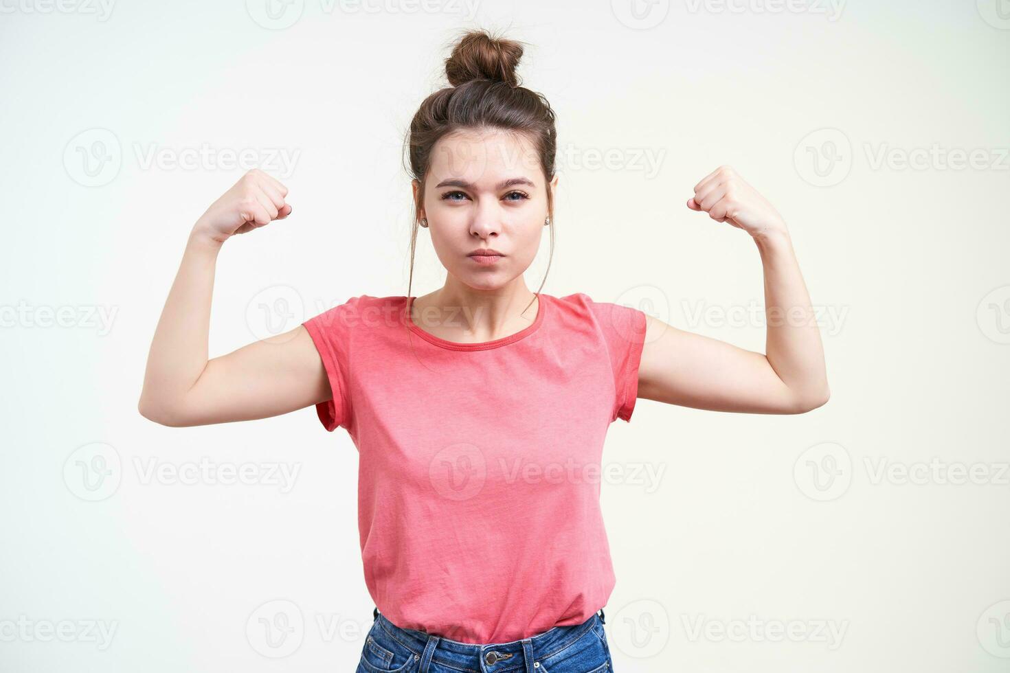 echt jong mooi bruin haren vrouw met bun kapsel balanceren vuisten terwijl demonstreren macht met verheven handen, staand over- wit achtergrond foto