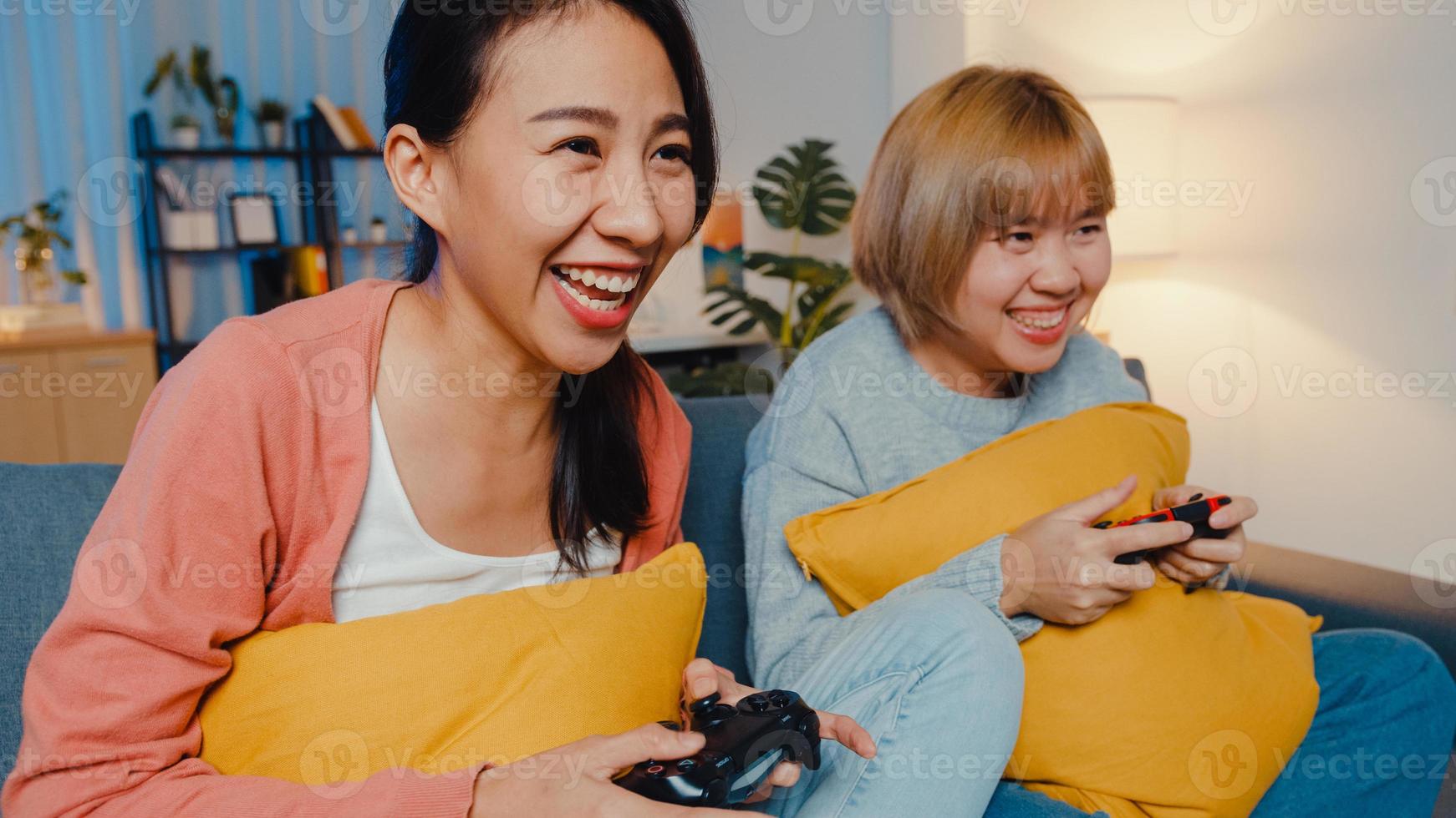 lesbische lgbtq-vrouwen spelen thuis een videogame. jonge Aziatische dame met behulp van draadloze controller met grappig gelukkig moment op de bank in de woonkamer 's nachts. ze hebben een geweldige en leuke tijd om vakantie te vieren. foto