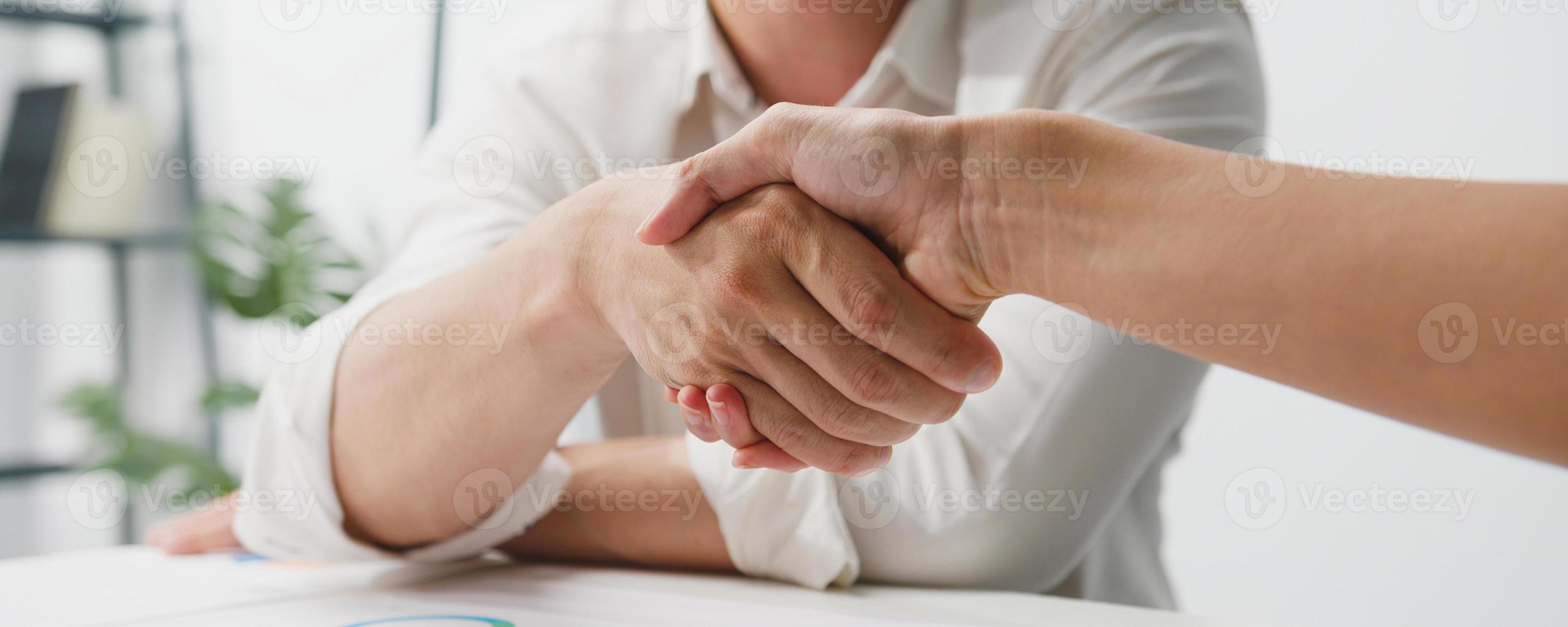 jonge creatieve mensen in slimme vrijetijdskleding bespreken zaken die elkaar de hand schudden op kantoor. partnersamenwerking, teamwerkconcept voor collega's. panoramische bannerachtergrond met exemplaarruimte. foto