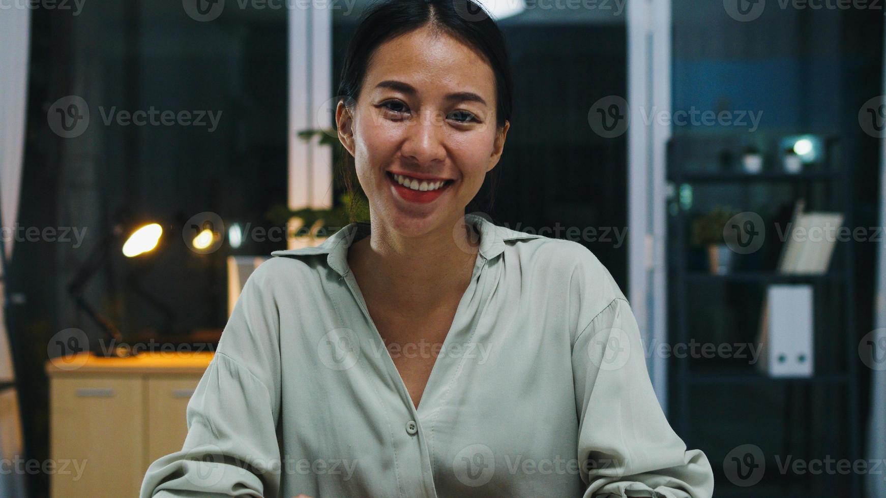 portret van mooie zakenvrouw slimme vrijetijdskleding kijken naar de camera en glimlachen, gelukkig in moderne kantoor werkplek nacht. jonge aziatische dame praat met collega in videogesprek thuis. foto