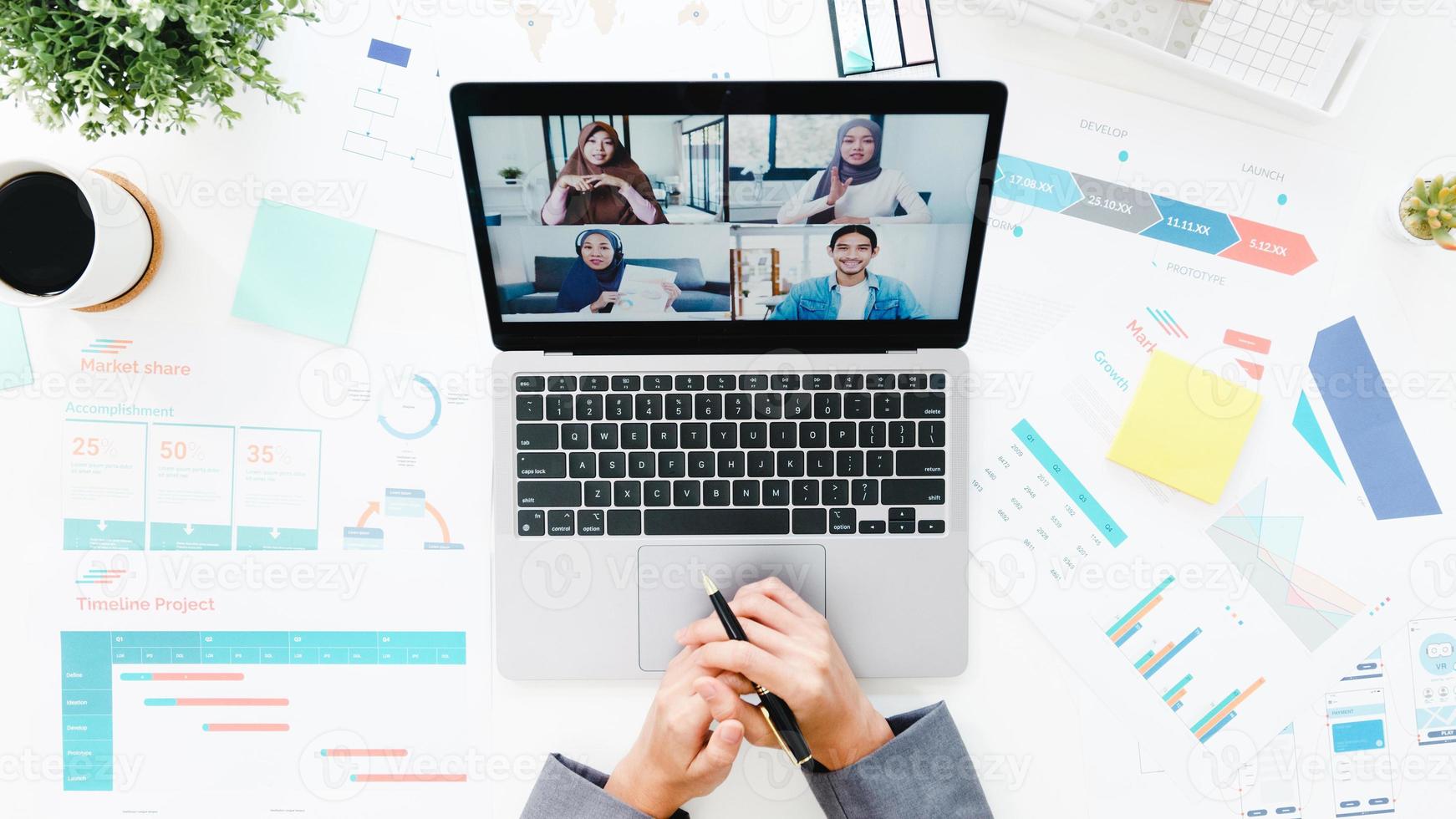 bovenaanzicht van jonge Aziatische zakenvrouw die laptop gebruikt, praat met collega over plan in videogesprekvergadering terwijl ze vanuit huis in de woonkamer werkt. sociale afstand, quarantaine voor preventie van het coronavirus. foto