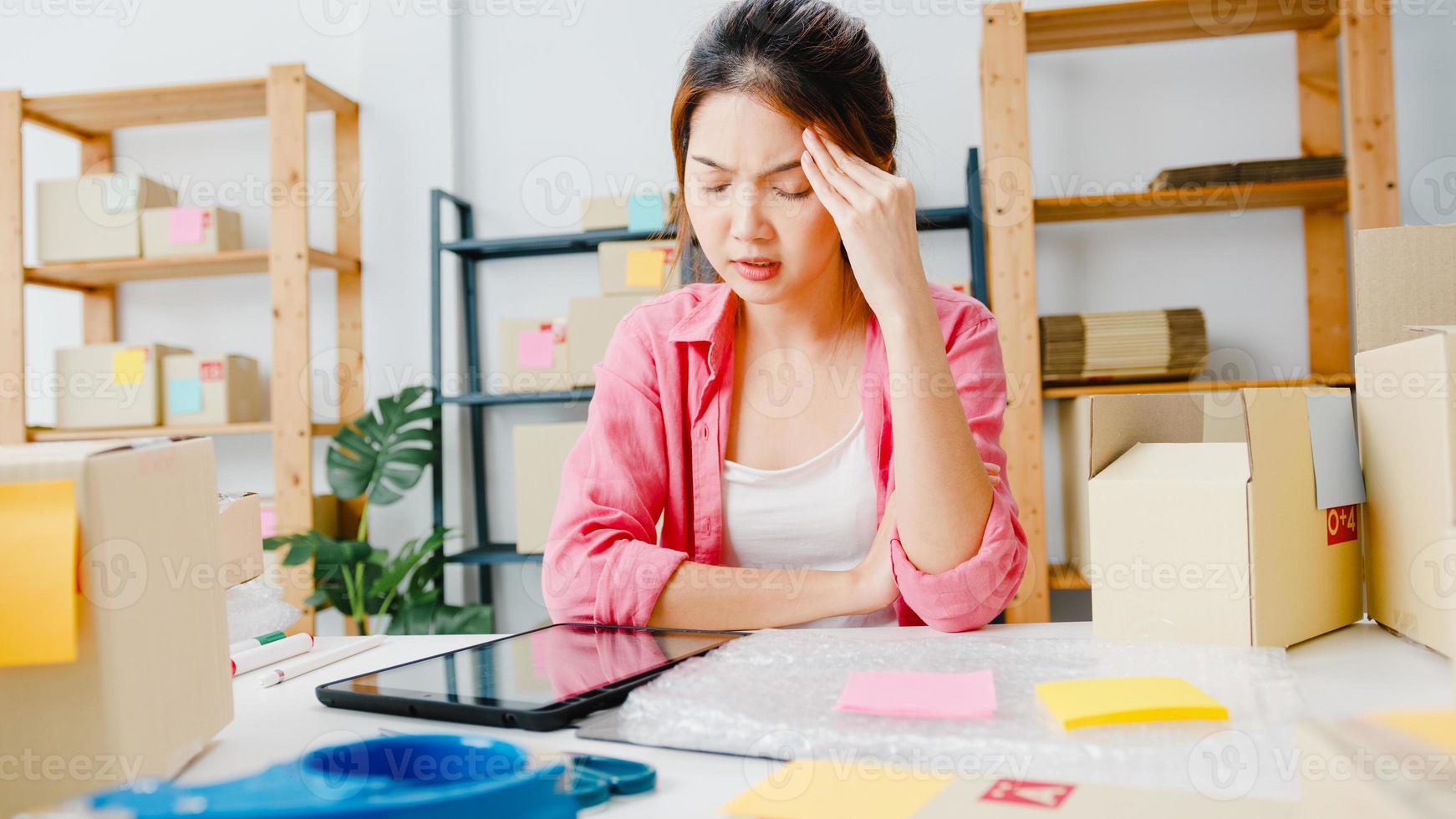 jonge azië ondernemer zakenvrouw check product inkooporder op voorraad, met behulp van tablet hard werk overbelasting op kantoor aan huis. eigenaar van een klein bedrijf, online marktlevering, lifestyle freelance concept. foto