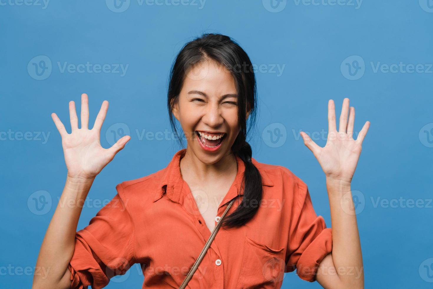 jonge Aziatische dame voelt geluk met positieve uitdrukking, vrolijke verrassing funky, gekleed in casual doek en kijkend naar camera geïsoleerd op blauwe achtergrond. gelukkige schattige blije vrouw verheugt zich over succes. foto