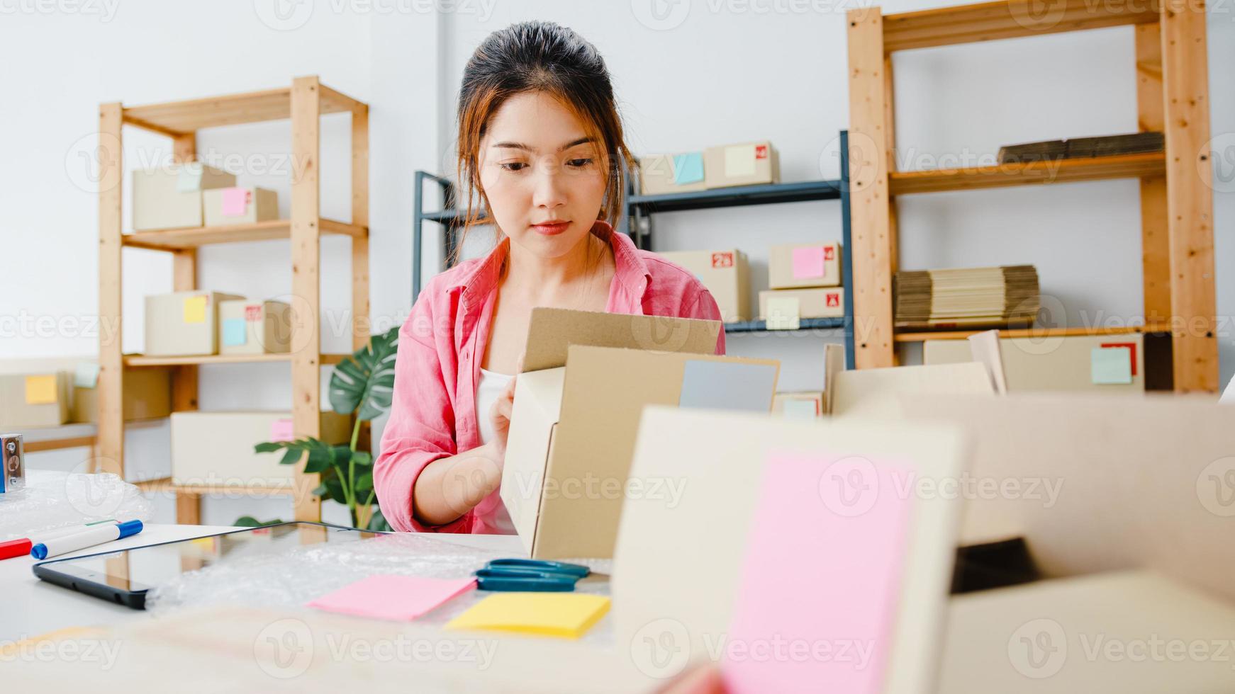 jonge azië ondernemer zakenvrouw check product inkooporder op voorraad en opslaan op tablet computer werk thuis kantoor. eigenaar van een klein bedrijf, online marktlevering, lifestyle freelance concept. foto