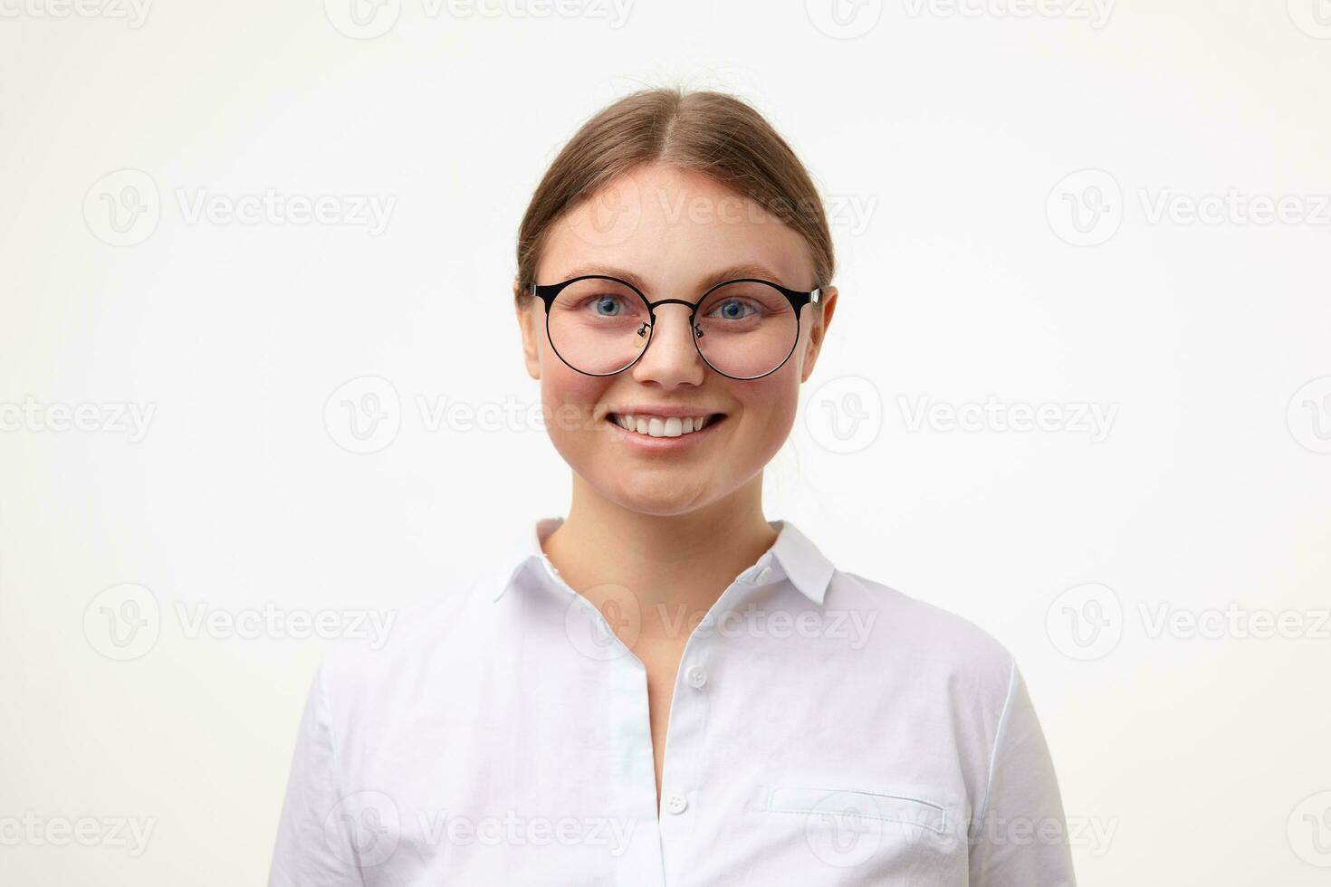 portret van jong blauwe ogen blond vrouw in bril tonen haar perfect wit tanden terwijl op zoek graag Bij camera, staand over- wit achtergrond in wit overhemd foto