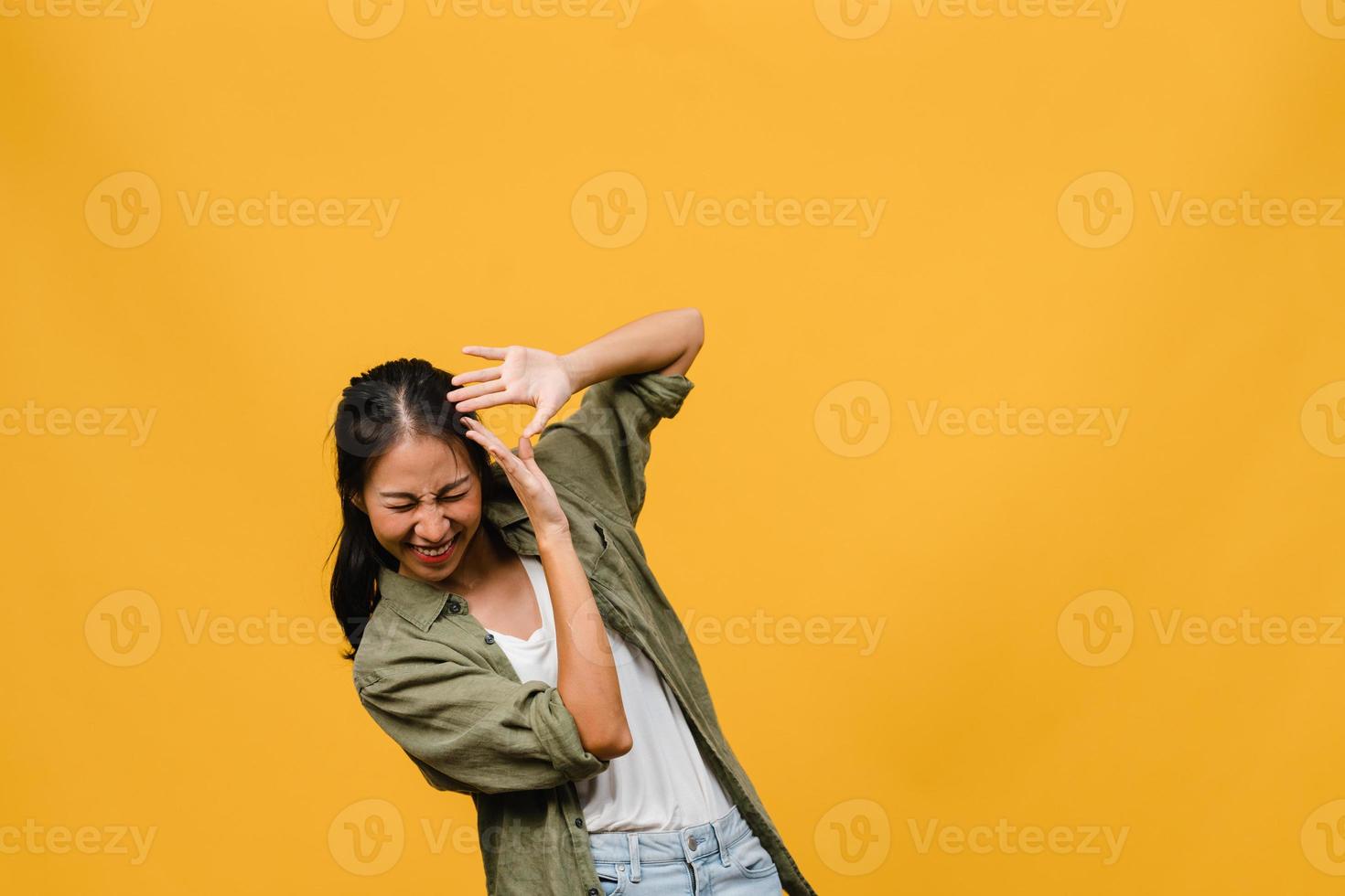 portret van jonge Aziatische dame met positieve uitdrukking, breed glimlachen, gekleed in casual kleding op gele achtergrond. gelukkige schattige blije vrouw verheugt zich over succes. gezichtsuitdrukking concept. foto