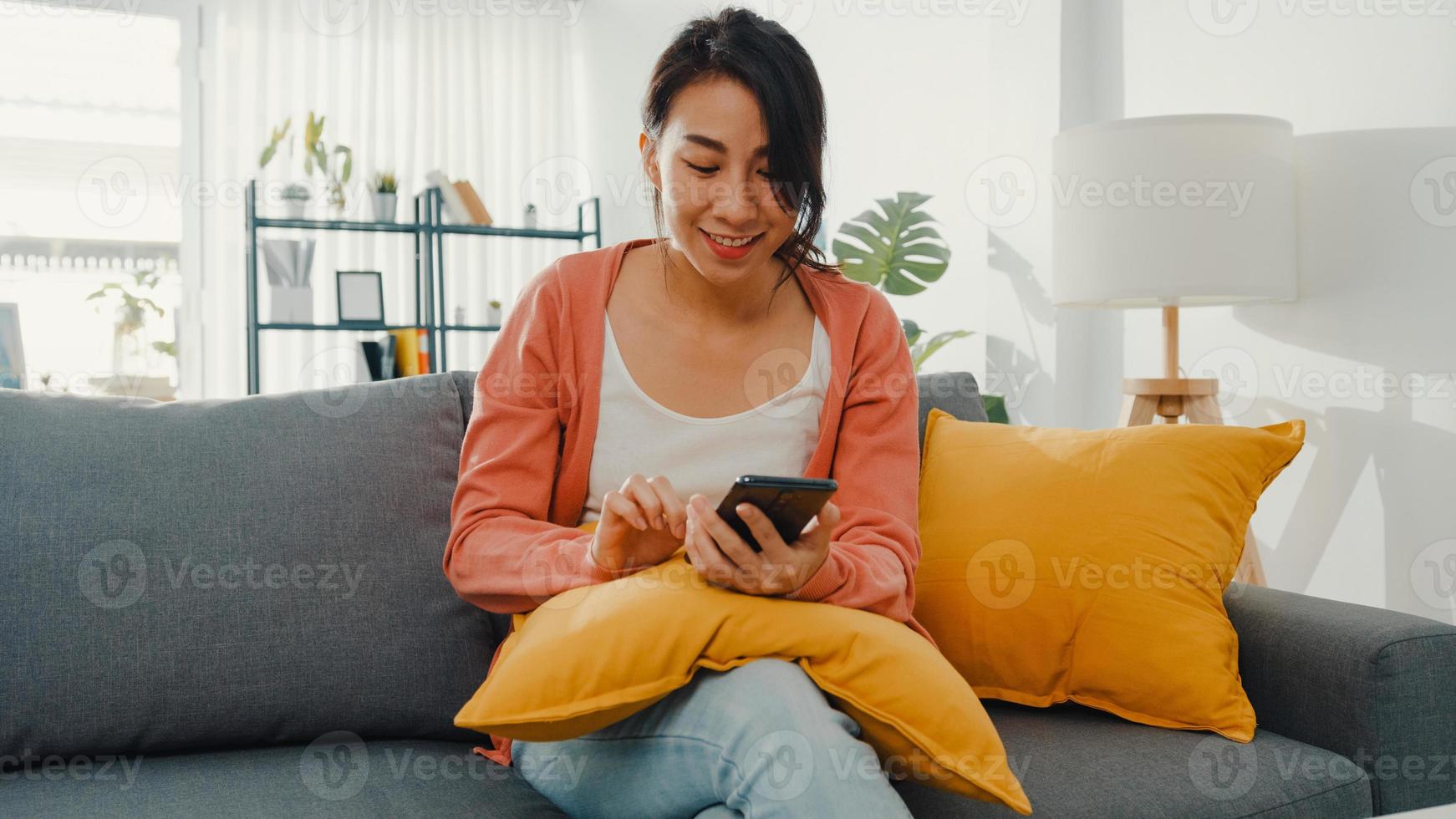 mooie dame met behulp van smartphone chat met paar zittend op de bank in de woonkamer thuis in de ochtend. blijf thuis, quarantaine voor covid, nomofobie, online winkelen, sociaal netwerkverslavingsconcept. foto