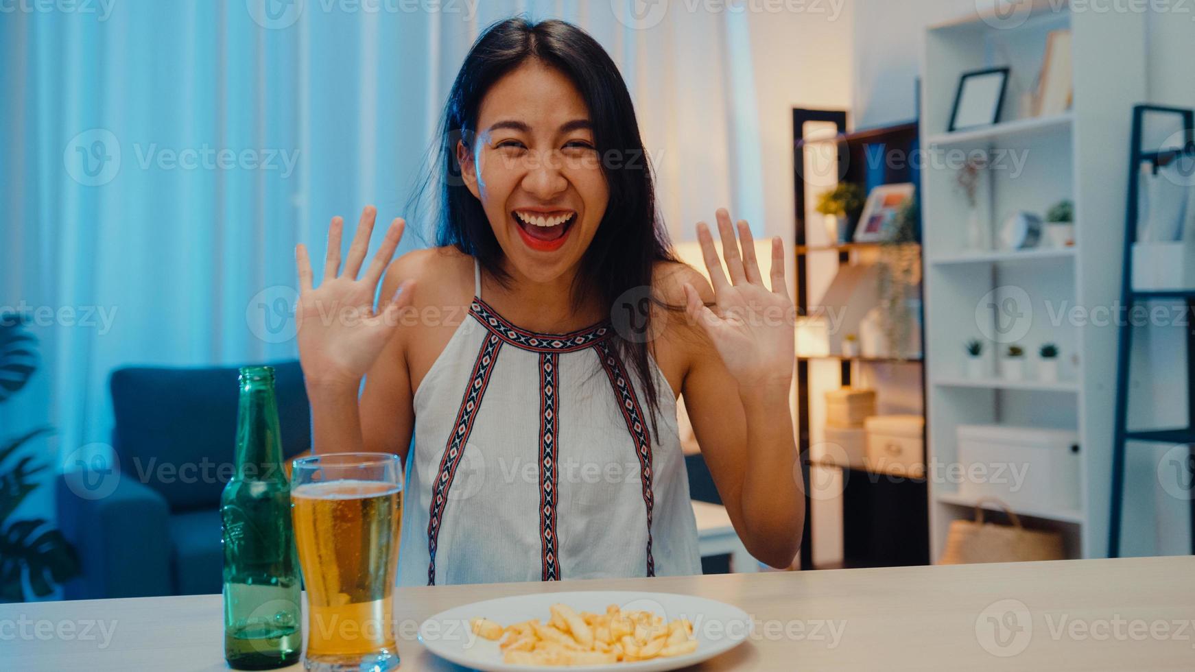 jonge aziatische dame die bier drinkt met plezier happy night party nieuwjaar evenement online viering via video-oproep per telefoon thuis 's nachts. sociale afstand, quarantaine voor coronavirus. oogpunt of pov foto