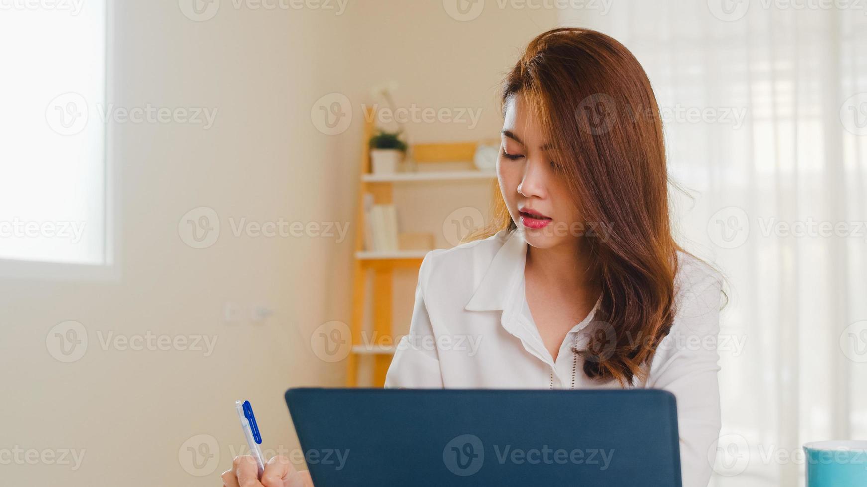 portret van freelance azië vrouwen vrijetijdskleding met behulp van laptop die in de woonkamer thuis werkt. thuiswerken, werken op afstand, zelfisolatie, sociale afstand, quarantaine voor coronaviruspreventie. foto