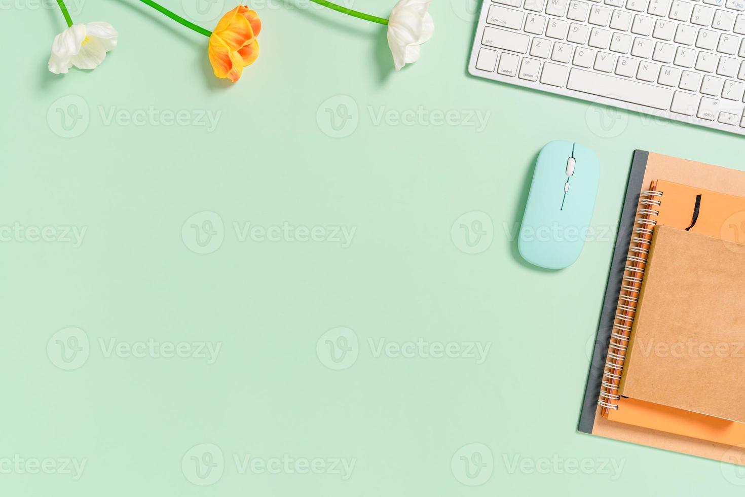 minimale werkruimte - creatieve platliggende foto van werkruimtebureau. bovenaanzicht bureau met toetsenbord, muis en notebook op pastel groene kleur achtergrond. bovenaanzicht met kopieerruimte, platliggende fotografie.